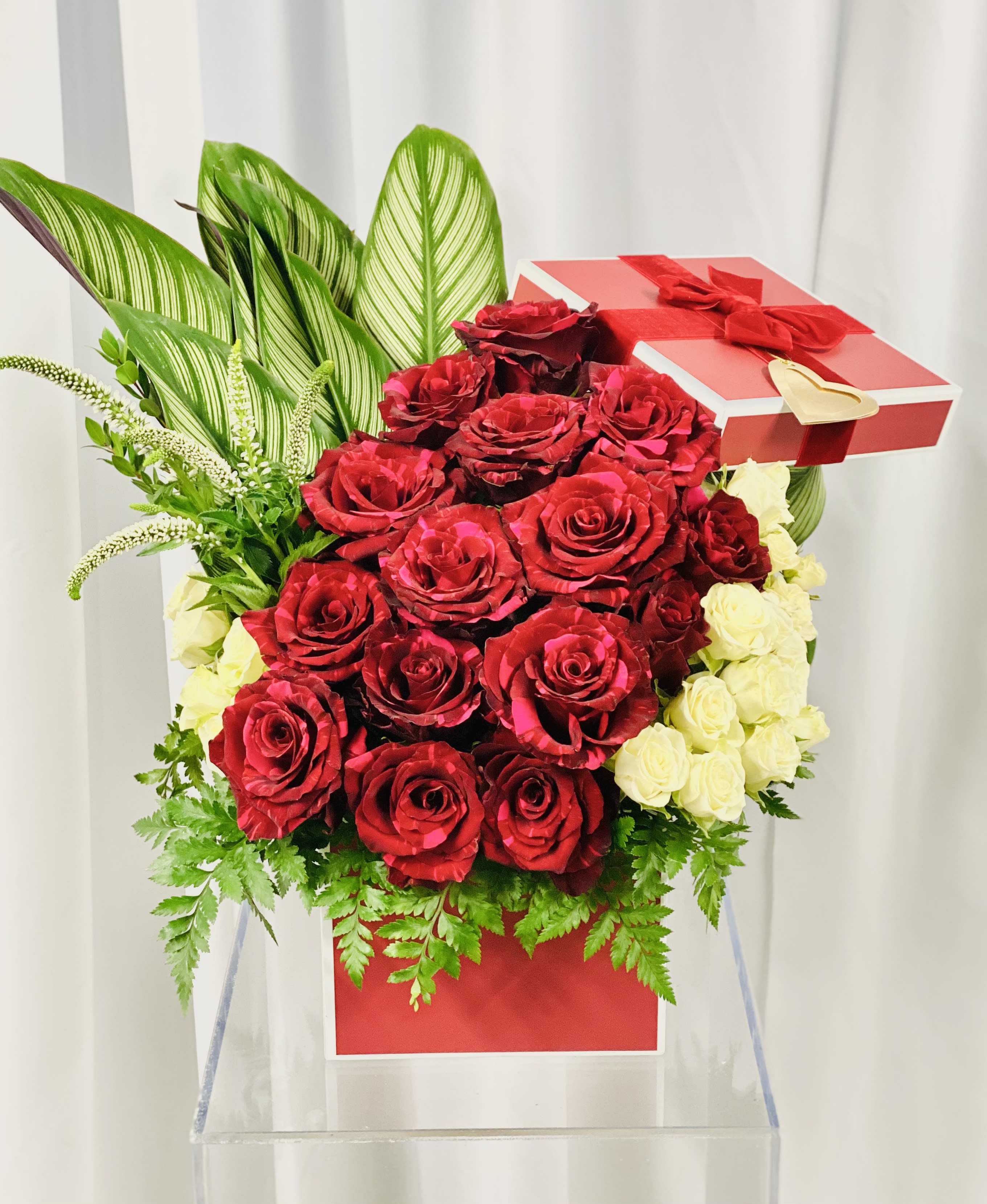 Dangerously In Love - A beautiful display of pink panther red roses and white spray roses accented with greenery and white fillers.  Florals set in a box topped with the topper. This design is sure to bring a smile to your loved one's face!