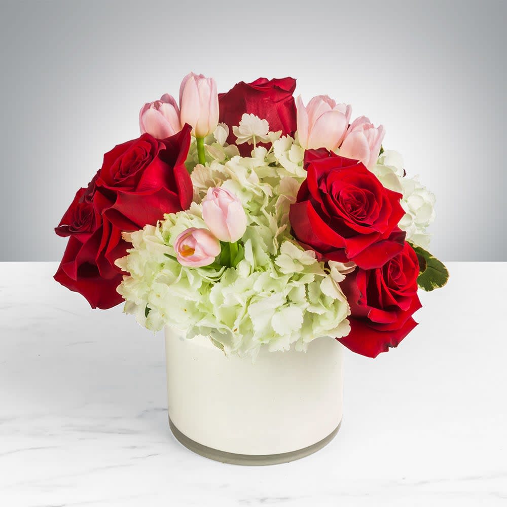 Blossoming Romance by BloomNation™   - Blossoming Romance by BloomNation™ is the perfect gift to wish someone a happy birthday or to say thank you. White cylinder is not available, clear cube will be used.   Arrangement Details:  This arrangement includes red roses, pink tulips, and white hydrangea in a clear cube. APPROXIMATE DIMENSIONS: 12&quot; H X 11&quot; W