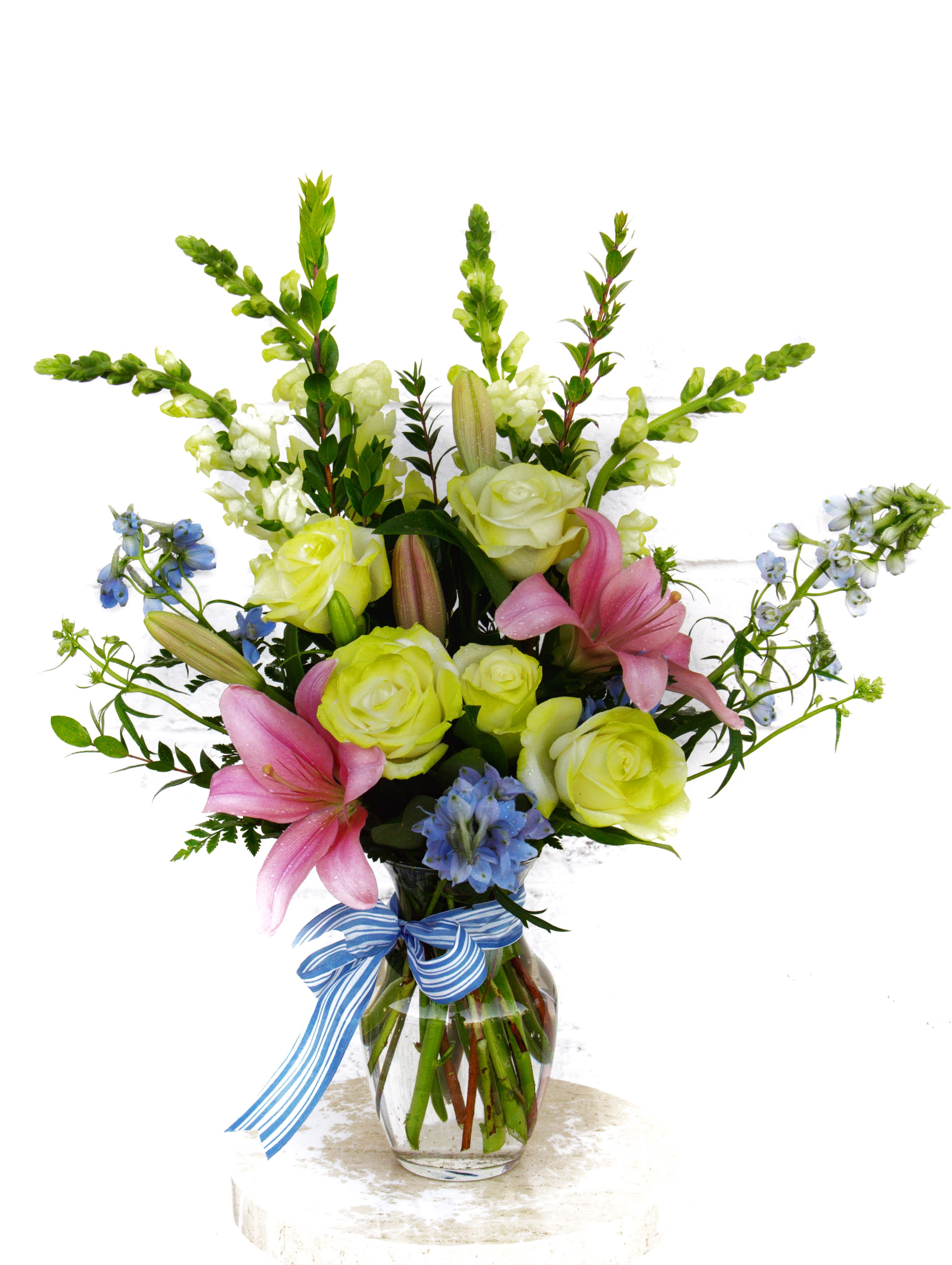 A Beach Day - Pretty design including snapdragon, lilies, roses, delphiniums with accents in a glass vase.