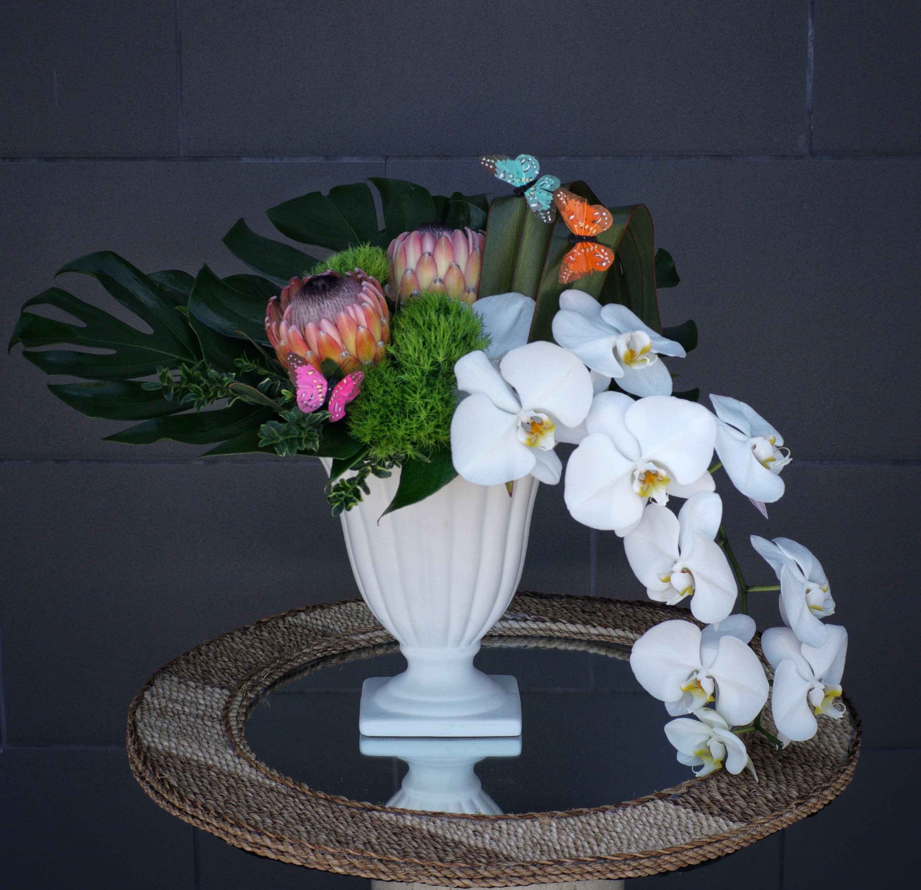 Orchid Embrace - This elegant design includes orchids, big protea and tropical accents in a nice vase