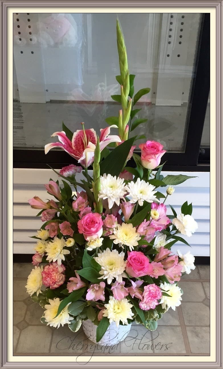 CF796 - Soft pink tones and creamy whites are combined to create this floral masterpiece. Blush Beauty features a lush assortment of pink roses, carnations, gladiolus, stargazer lilies, alstroemerias, white chrysanthemums, and foliage artfully arranged in an elegant white basket. 