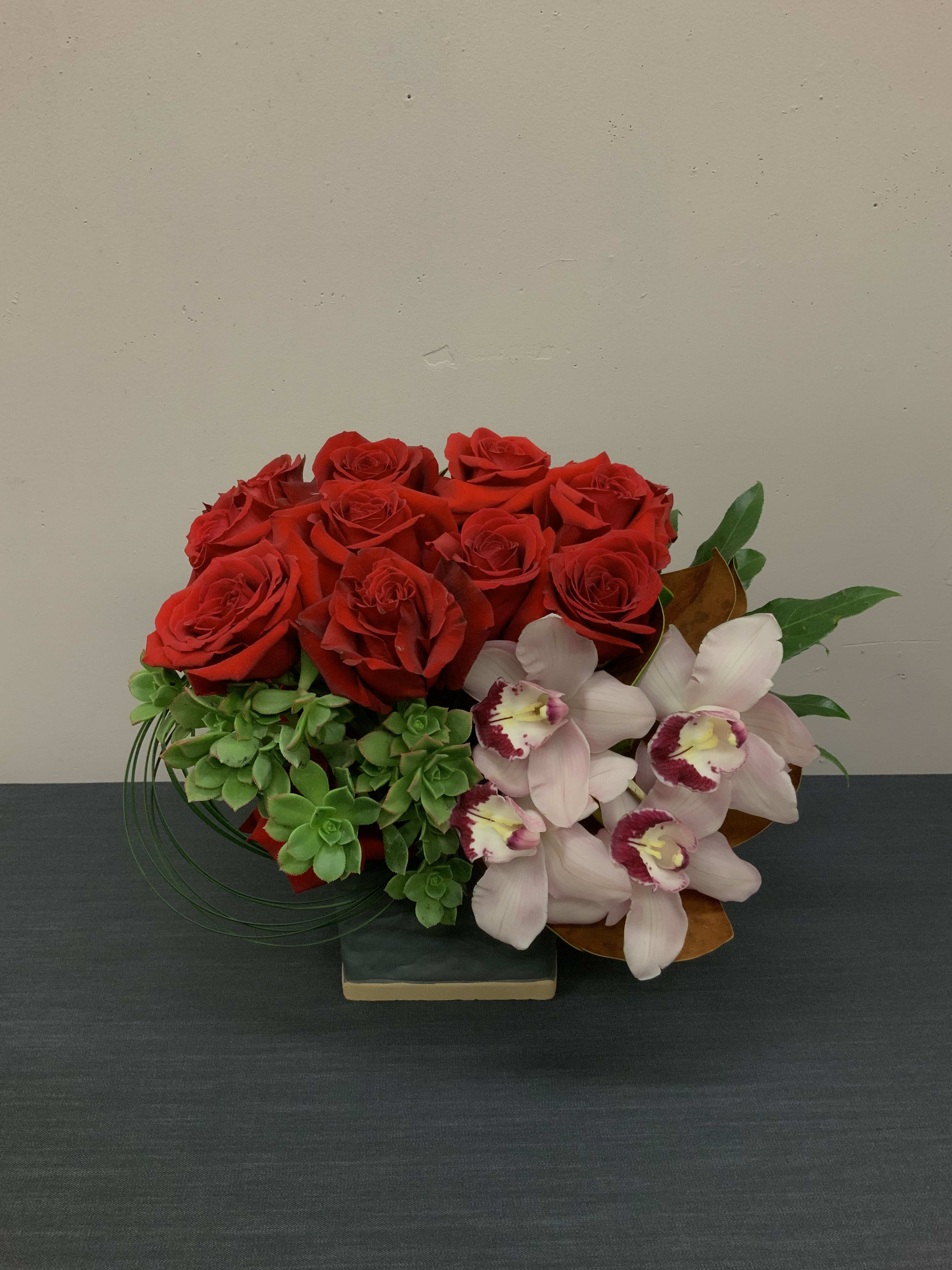 Amor - Twelve red roses complimented with cymbidium orchids, succulents, grass and greenery.