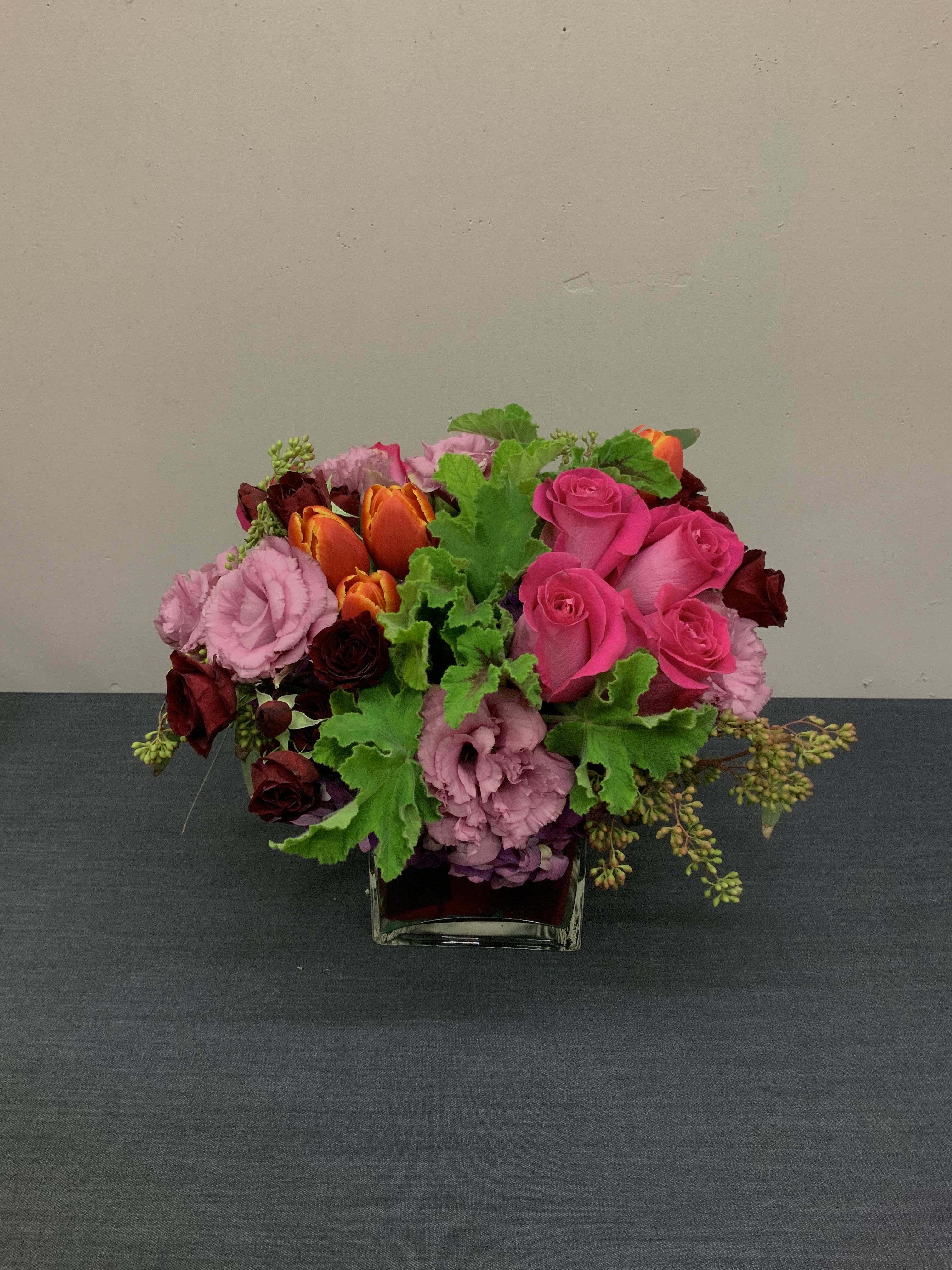 Colorful - Medium arrangement with hot pink roses, orange tulips, sprayed roses, hydranyas and a touch  lisianthus.