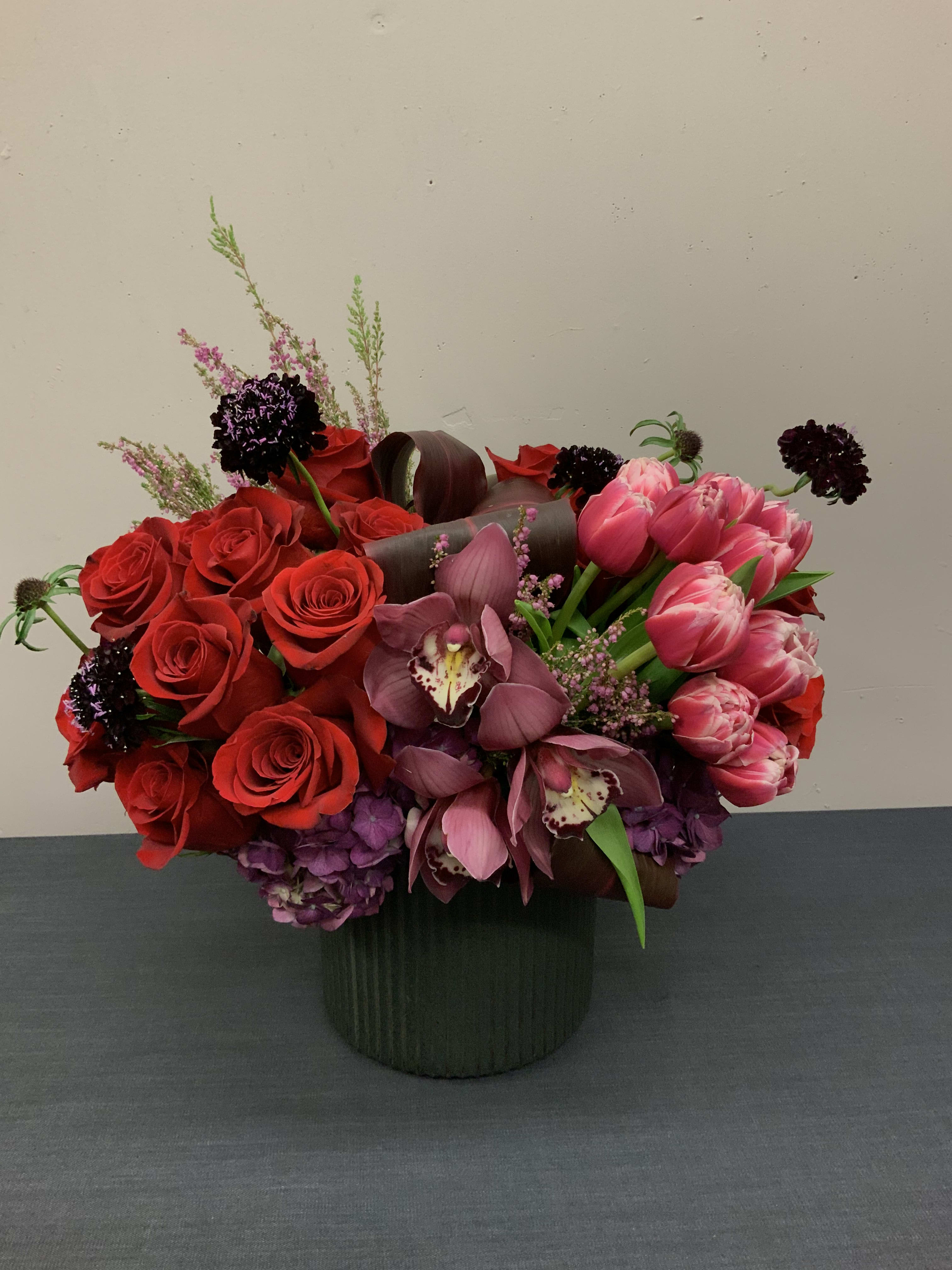 Kiss me Kate - Beautiful arrangement in an 8x8in vase with red roses, pink tulips, vanda orchids, scabiosa, hydrangea, and a touch of heather.  