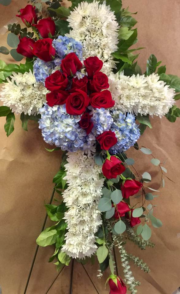 Red, White & Blue Peaceful Tribute Red, White & Blue Peaceful Tribute - 36" Cross filled with white pom poms, blue hydrangea and beautiful red roses. This tribute is perfect for showing your love and respect to a service person. As shown has 20 red roses. If you would like to order this in different colors, please specify in the "Special Instructions" part of your order. If we are unable to fulfill your request, we will call you to discuss alternatives.