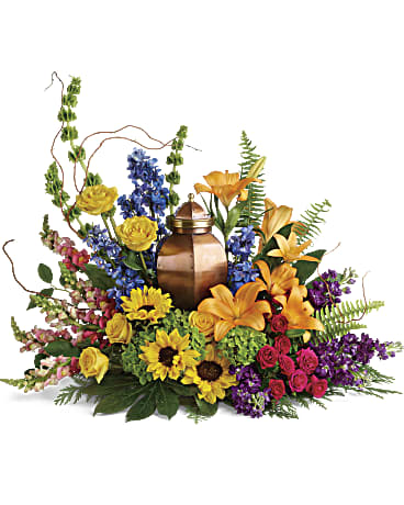 With All Our Hearts Cremation Tribute - This colorful bouquet of hydrangea, roses, and sunflowers brings a bright light of hope to the cremation urn and celebration of life. This colorful arrangement includes green hydrangea, yellow roses, hot pink spray roses, orange asiatic lilies, yellow sunflowers, bells of Ireland, blue delphinium, orange snapdragons, purple stock, curly willow, cedar stem, sword fern, aralia leaf, and lemon leaf. Arrangement does not include urn. 33Wx27H
