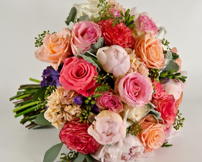 Lovely - A beautiful arrangement of blush peonies ( seasonal), coral and pink  roses, peach stock, accent with eucalyptus and purple freesia.  Peonies may be sub with garden roses. ** ALL BRIDAL MUST BE ORDER 2 WEEKS IN ADVANCE. If there is less than 2 weeks, please contact the design department at 619-295-3444 Ext:103