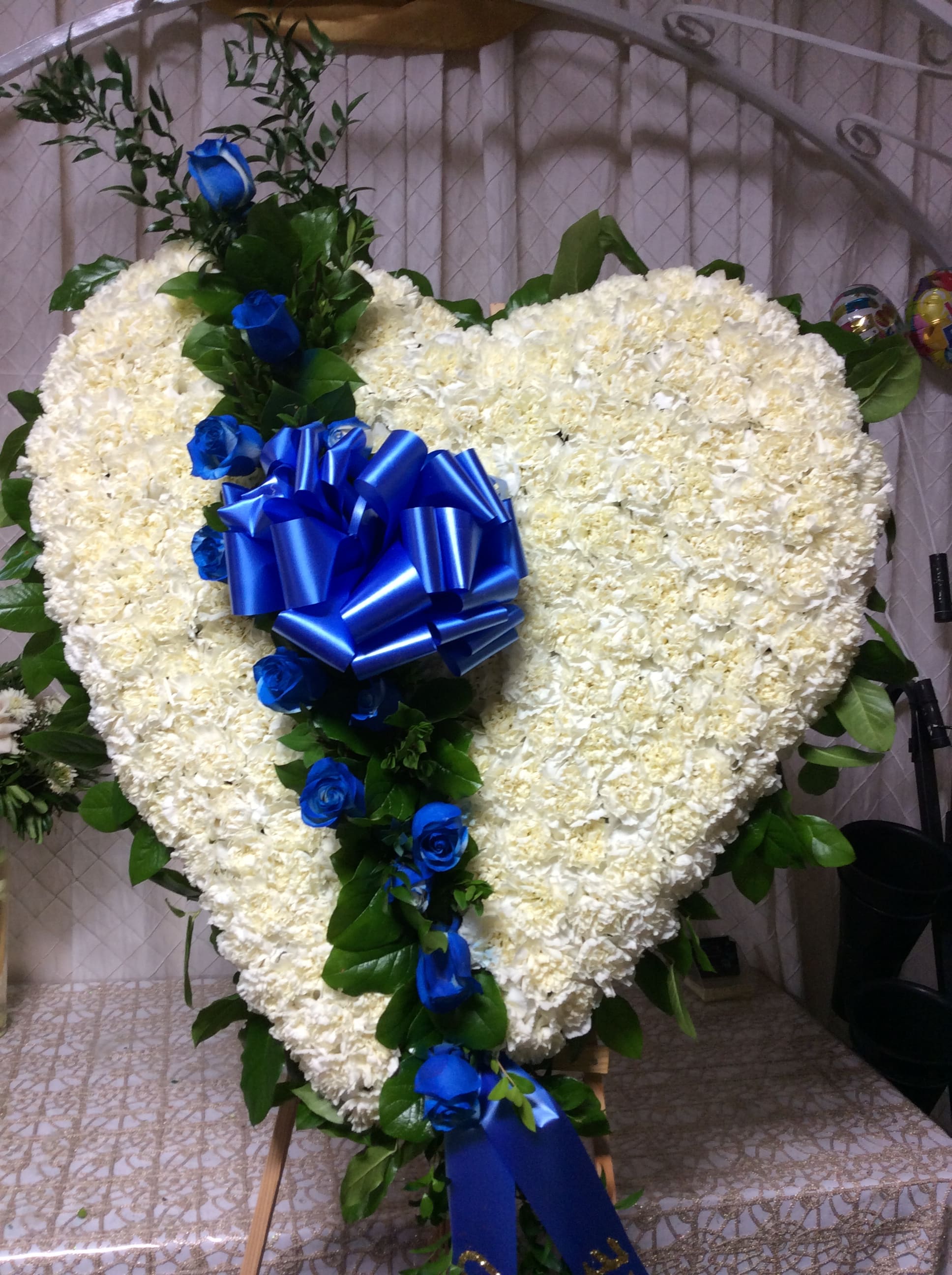 Royal Heart Standing Sympathy Arrangement Royal Heart Standing Sympathy Arrangement - White heart filled with Carnations. Touch of Royal Blue Roses and ribbon .