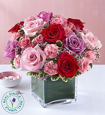 Eternally Yours Rose Bouquet - Our romantic bouquet looks like it came fresh from the garden! We’ve gathered gorgeous red, pink and lavender roses with pink mini carnations and limonium for a delightful, delicate color palette. Artistically hand-designed inside a modern cube vase lined with Ti leaf ribbon, our striking bouquet elegantly conveys the sentiment: “I’m forever yours.”