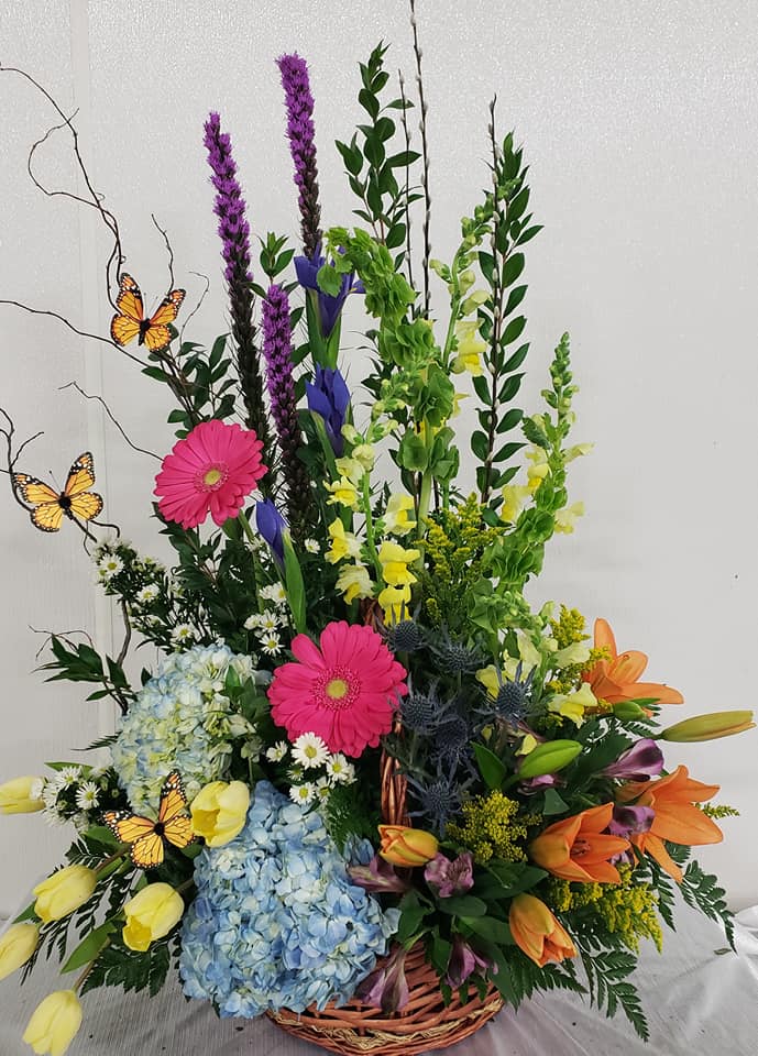 Deb's Bright and Bold Spring Garden - This one sided bold arrangement features, Hot pink Gerbera daisies, orange lillies, blue hydrangeas, bells of ireland  yellow snaps, iris to make a bright and bold spring like arrangement