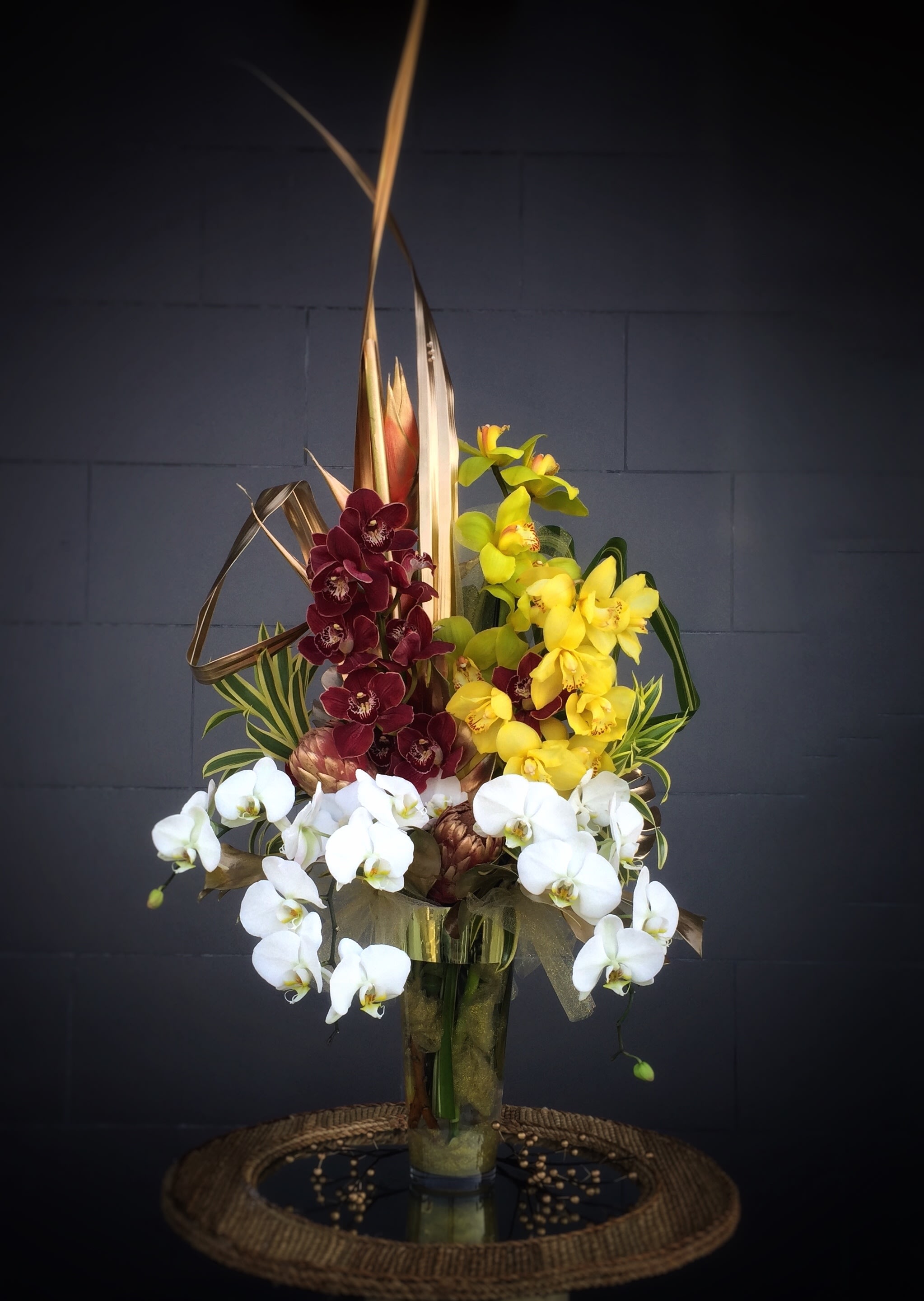 Magnificence - Luxury design including Cymbidium orchids, Phalaenopsis orchids and tropical accents in a  gold vase.