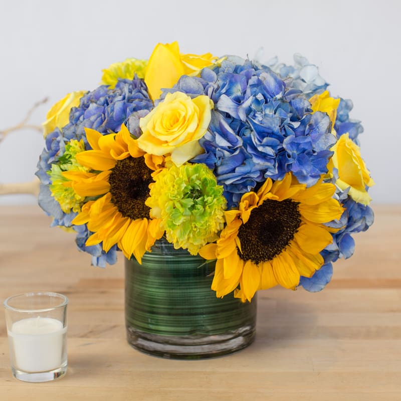 Sunny Day Blooms - Want an arrangement that captures the memory of the perfect summer's day? This is the perfect arrangement to get rid of those cloudy days. Containers come in clear, white, black, and leaf line.   It's possible that some days we may not have the exact flowers depending on the season, or exact container specified on the arrangement's description. When this is the case, our bouquets are made with flower substitutions or delivered in a different vase than expected by using substitutions of an equal or higher value. If you'd prefer no substitutions, please send an email or call us after placing your order. Please give us at least three days notice if you're looking for an arrangement with no substitutions.