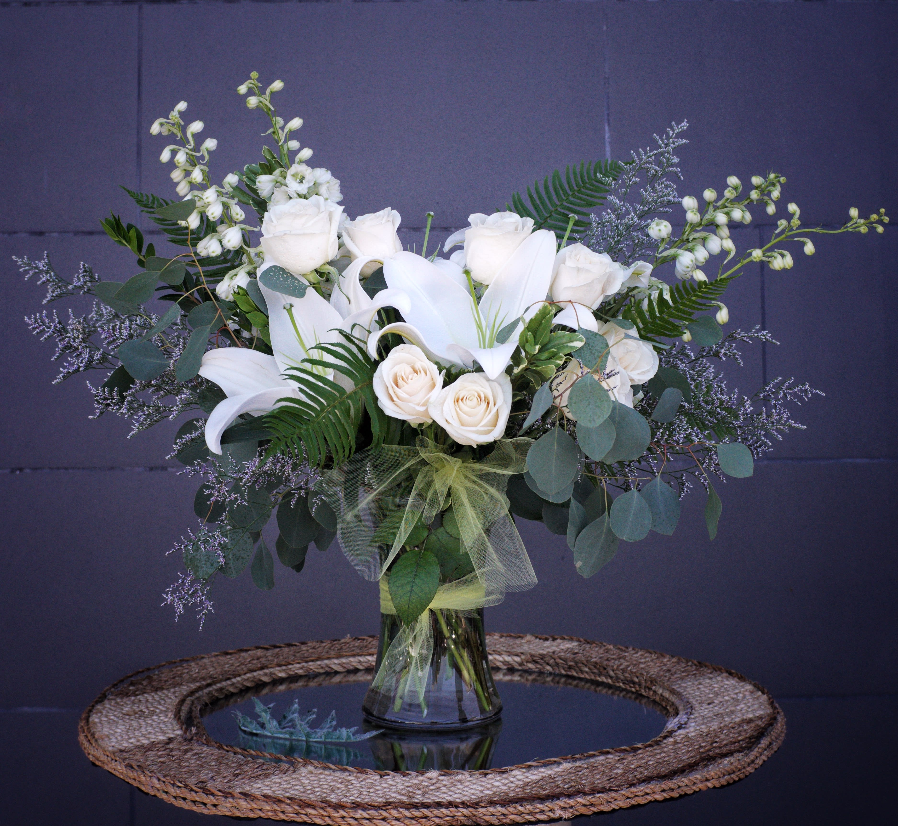 Classic All White - A classic all white design with all premium flowers: lilly, hydrangea, rose, larkspur and accents in a tall glass vase. STANDARD AS SHOWN: FIRST PHOTO DELUXE: SECOND PHOTO PREMIUM: THIRD PHOTO 