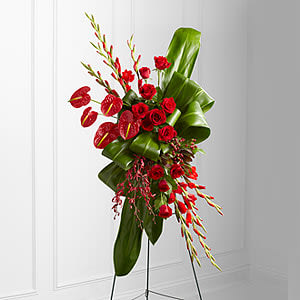 Sweet Thoughts Standing Spray - The Sweet Thoughts Standing Spray is an expression of sophistication and beauty to commemorate the life of the deceased at their final memorial service. Brilliant red roses, gladiolus, anthurium, James Storei orchids and hypericum berries create an exquisite arrangement offset by bright green ti and aspidistra leaves folded in a unique pattern to create a presentation symbolizing the unending love you have for the departed.  Displayed on a wire easel.