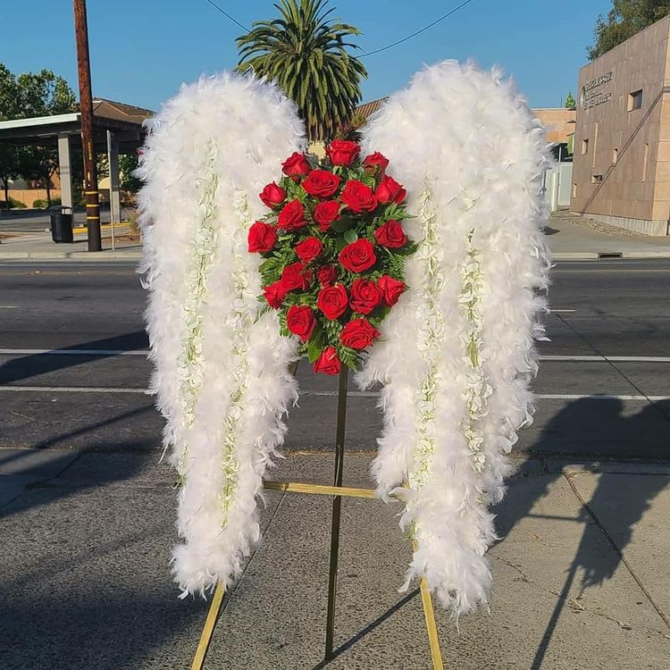 Fly High - All white wings, the wings are made up of feathers only. The center is made of roses, the color of the of the roses can be changed if requested. The height of the arrangement is approximately 6 ft. tall &amp; 3 ft. wide.