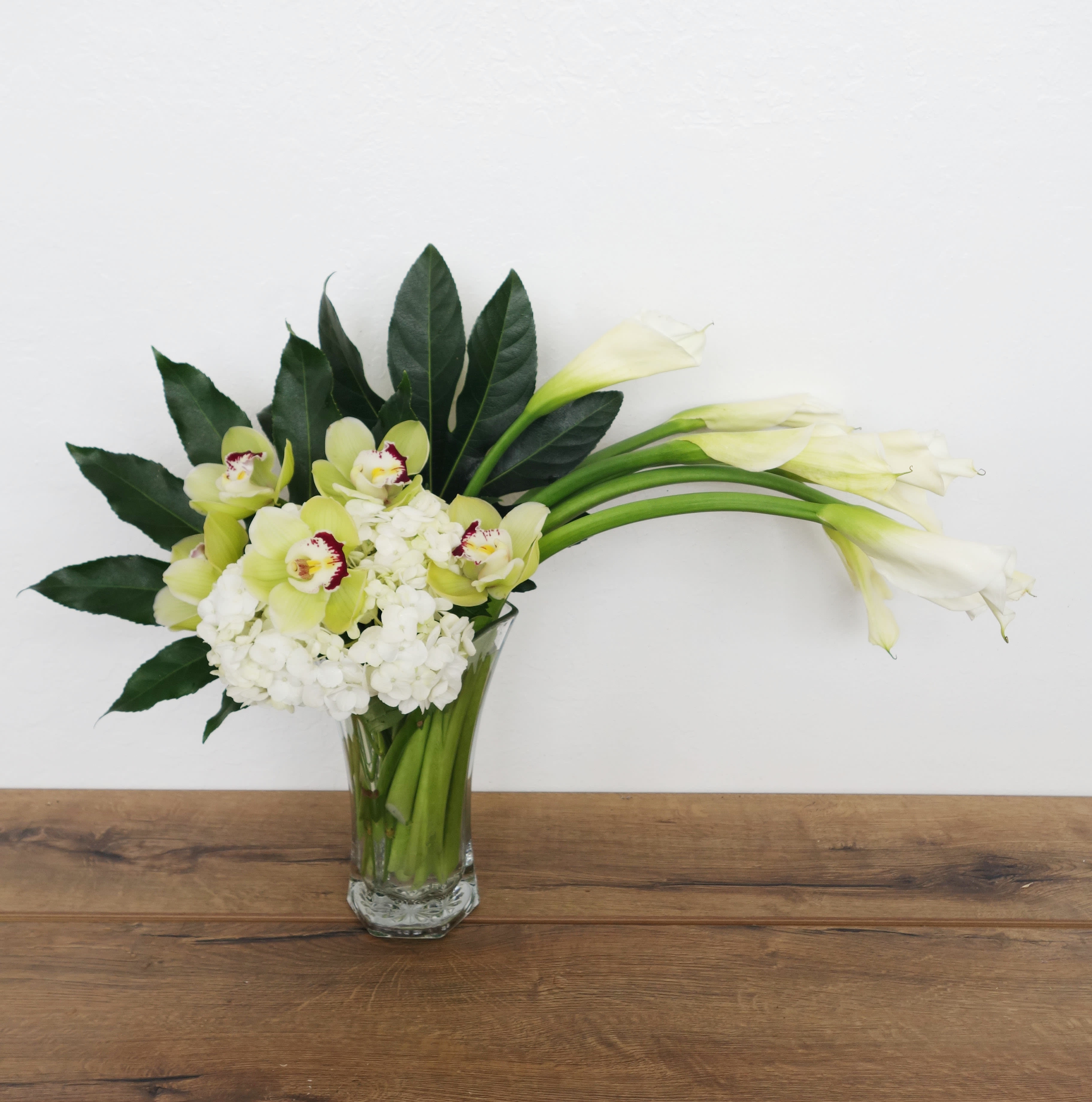 Moondance  - Moondance. Romance. Elegance! Captivating callas, white hydrangea, exotic orchids in a stunning tall glass vase create a green and white dream come true. No matter who you send this fabulous arrangement to, you can be sure it will impress!  Premium (as shown)  White callas, white hydrangea and green cymbidium orchids arrive in a graceful tall glass vase.  Approximately 29&quot; W x 20&quot; H  Orientation: One-Sided      As Shown : T79-1A     Deluxe : T79-1B     Premium : T79-1C  