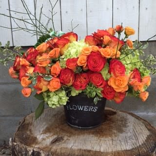 Orange bucket Orange bucket - Orange and peach roses mixed with green hydrangeas beautifully arranged in a flower bucket. Fun and rustic arrangement to brighten your home and bring in the sun.