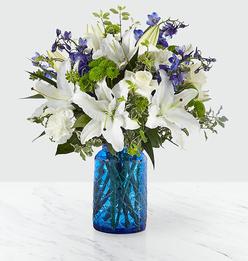 Healing Love™ Bouquet - The Healing Love™ Bouquet is a wonderful way to offer your heartfelt condolences for your special recipient's loss. Weaving together a bold assortment of blooms, this fresh flower arrangement consists of white roses, white Oriental Lilies, and white carnations with pops of blue delphinium and green buttom poms, accented with lush greens. Presented in a stylish bright blue embossed glass vase.