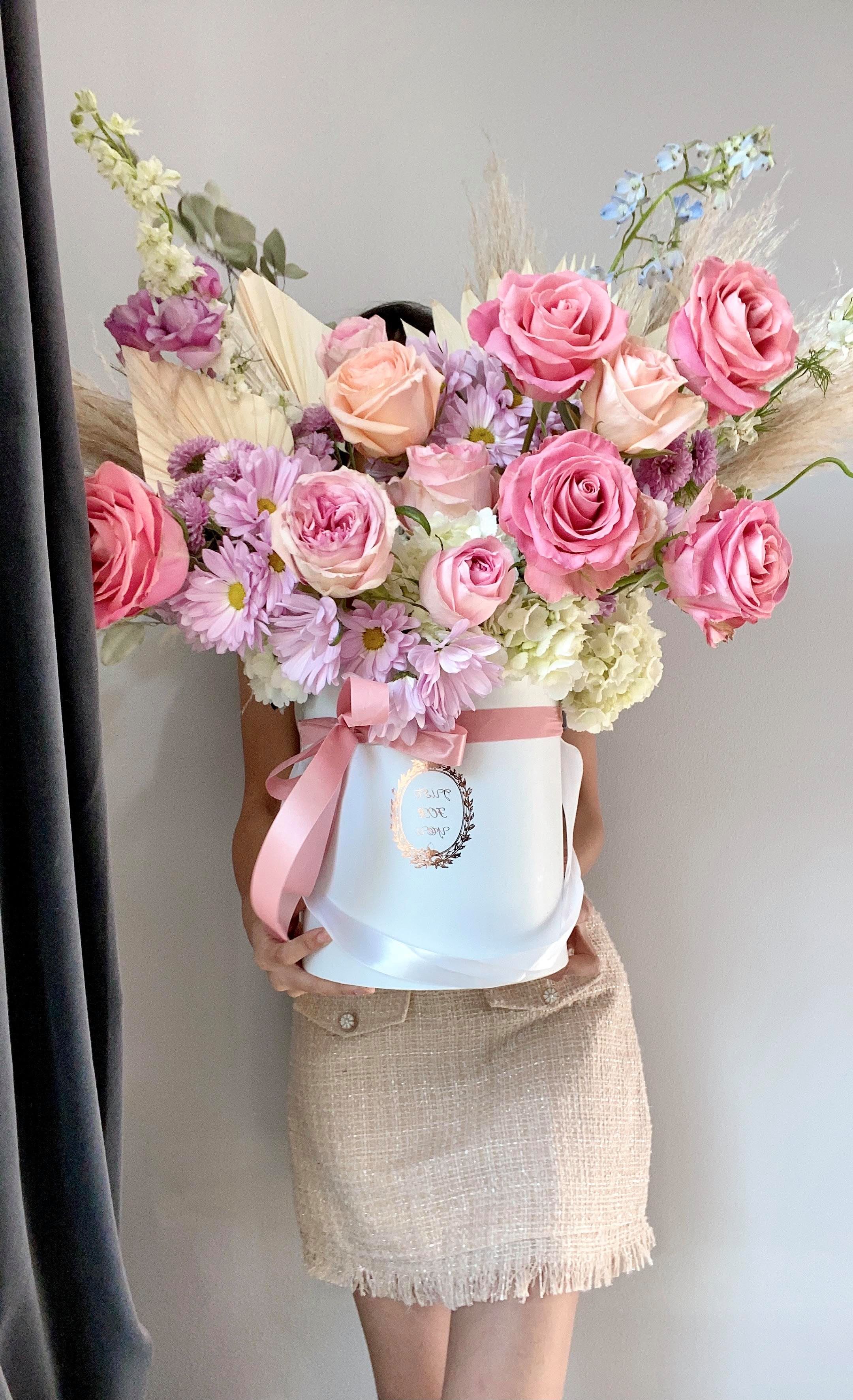SPRING FLING  - Sweet palette of muted shades of pastels fill this hat box with upmost elegance and grace. The combination of garden roses and soft pampas grass are every modern girl's dream in an arrangement of fleurs. Make that dream come true for your special one today!