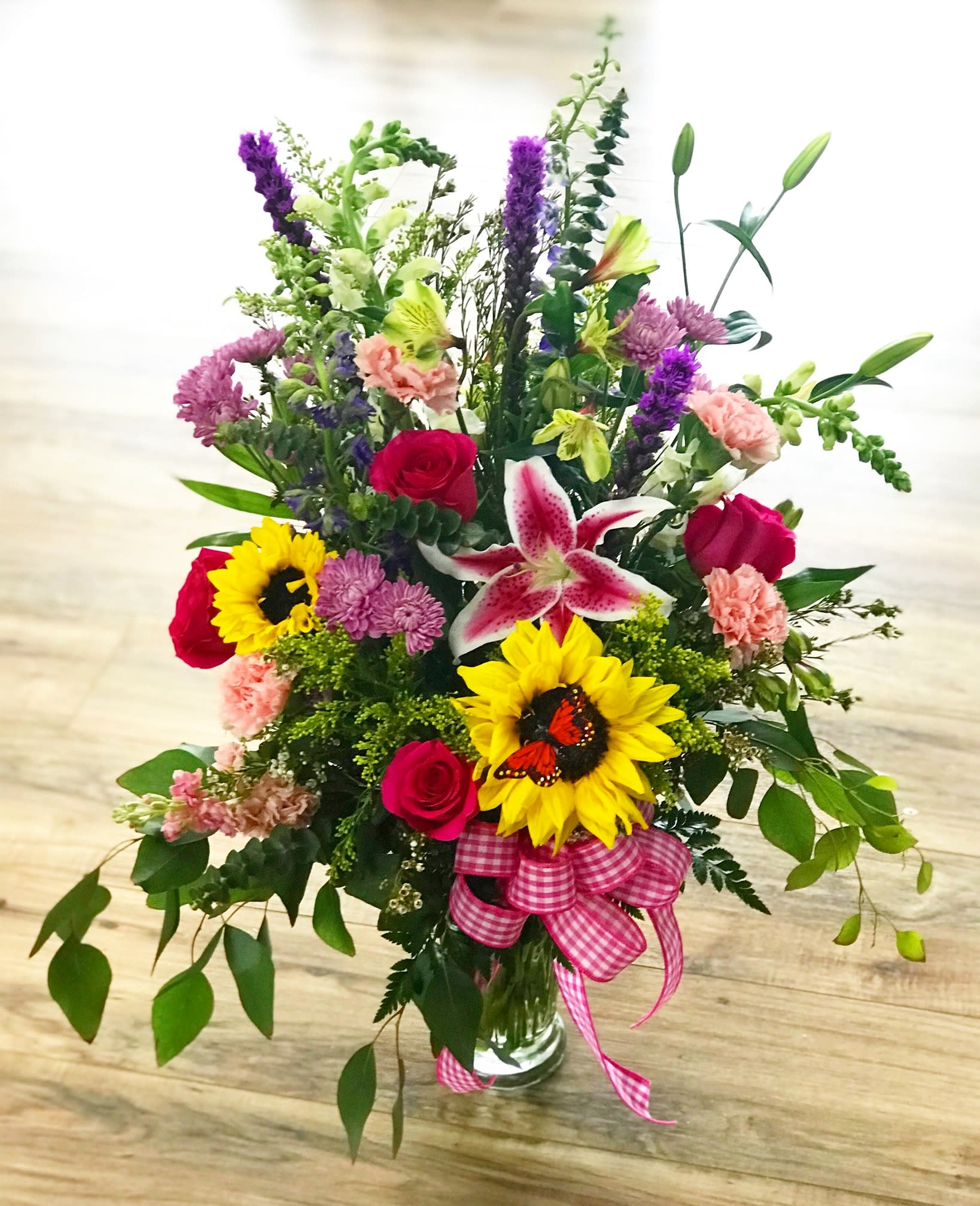 Spring Sensation - A beautiful mix of lilies, sunflowers, mums, roses and other fun colorful flowers. Includes a butterfly accent.