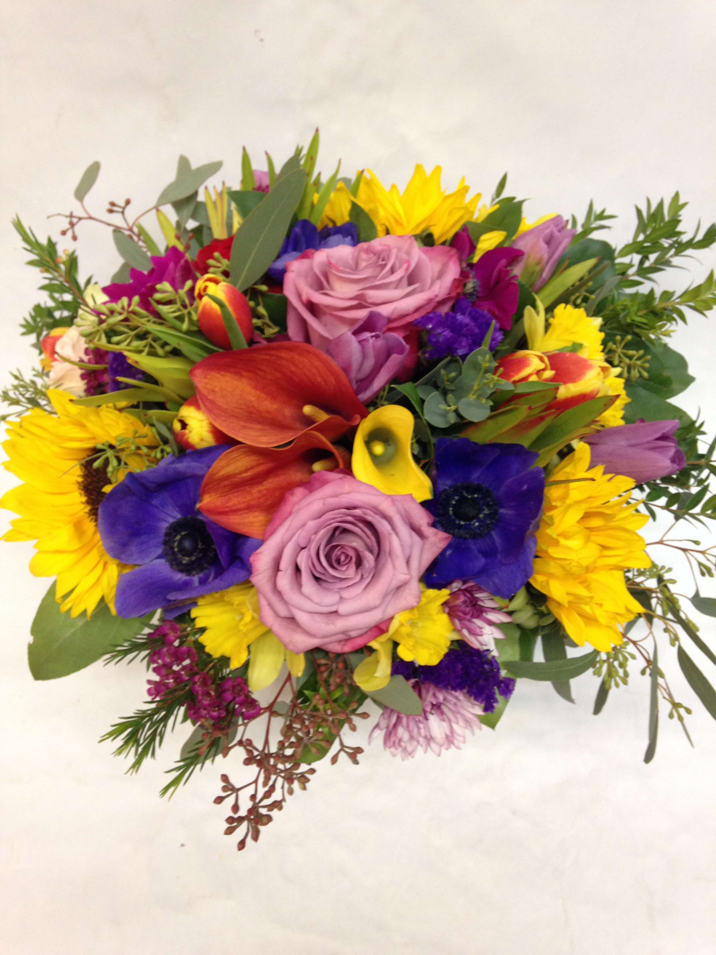Bold Blend Centerpiece Bold Blend Centerpiece - This low centerpiece is composed of multiple colors of sunflowers, calla lilies, roses, tulips, stock, soledago, eucalyptus and various greenery. (Some flowers may be subject to change depending on the season. We will contact you with available flower substitutions; please contact us with specific questions if you are concerned with flower availability, thanks!) Featured arrangement: $178.00.00 (Regular Price)