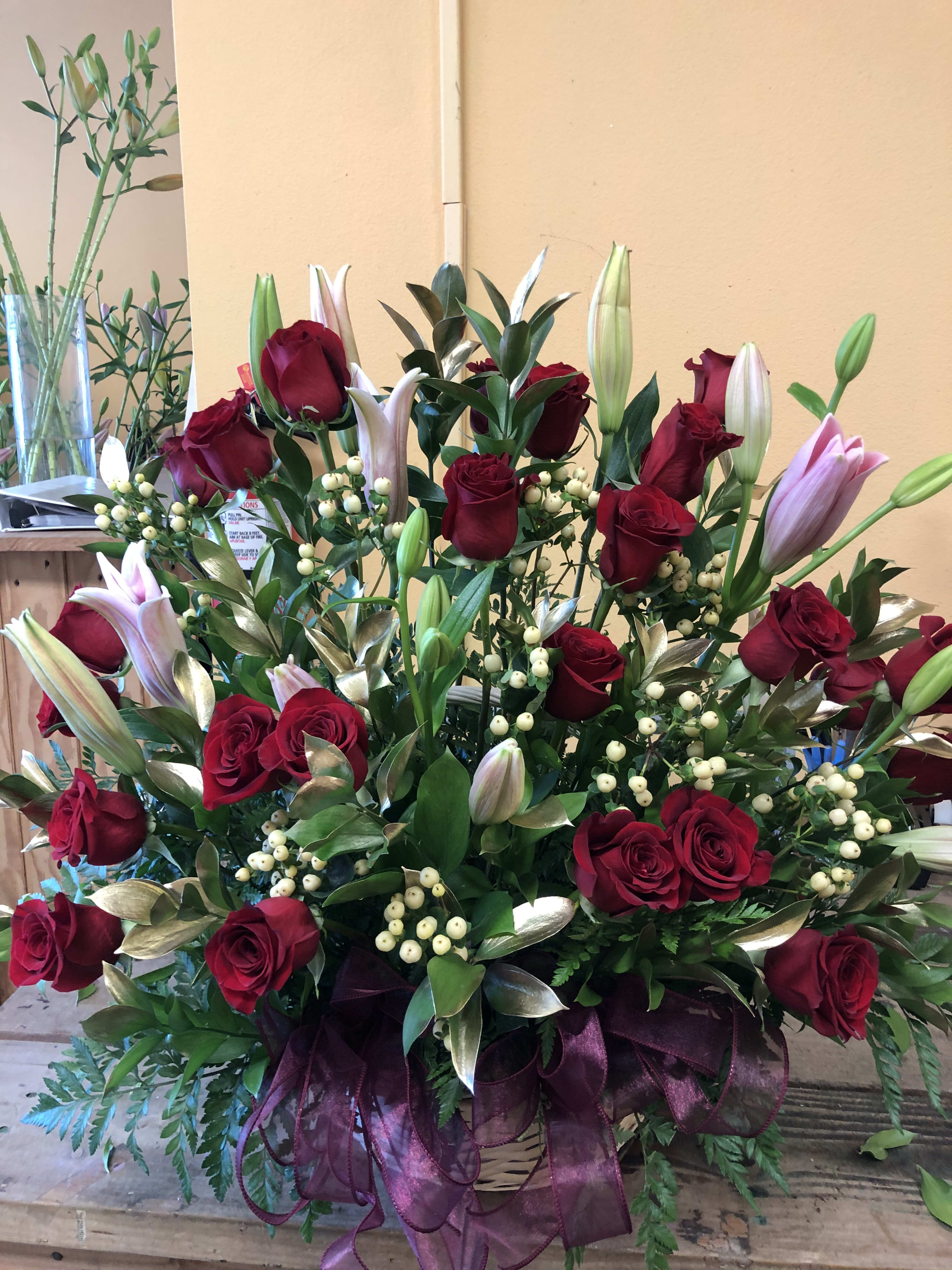 24 RED ROSES WITH LILIES (DESIGNER CHOICE LILIES) 24 RED ROSES WITH LILIES (DESIGNER CHOICE LILIES) - 24 RED ROSES WITH 4 LILIES (DESIGNER CHOICE LILIES WHAT EVER COLOR LILY WE HAVE AT THE TIME YOU PLACE THE ORDER). THE 24 RED ROSES WILL BE IN THIS ARRANGMENT WITH GOLD LEAVES AND HYPERICUM STEMS.