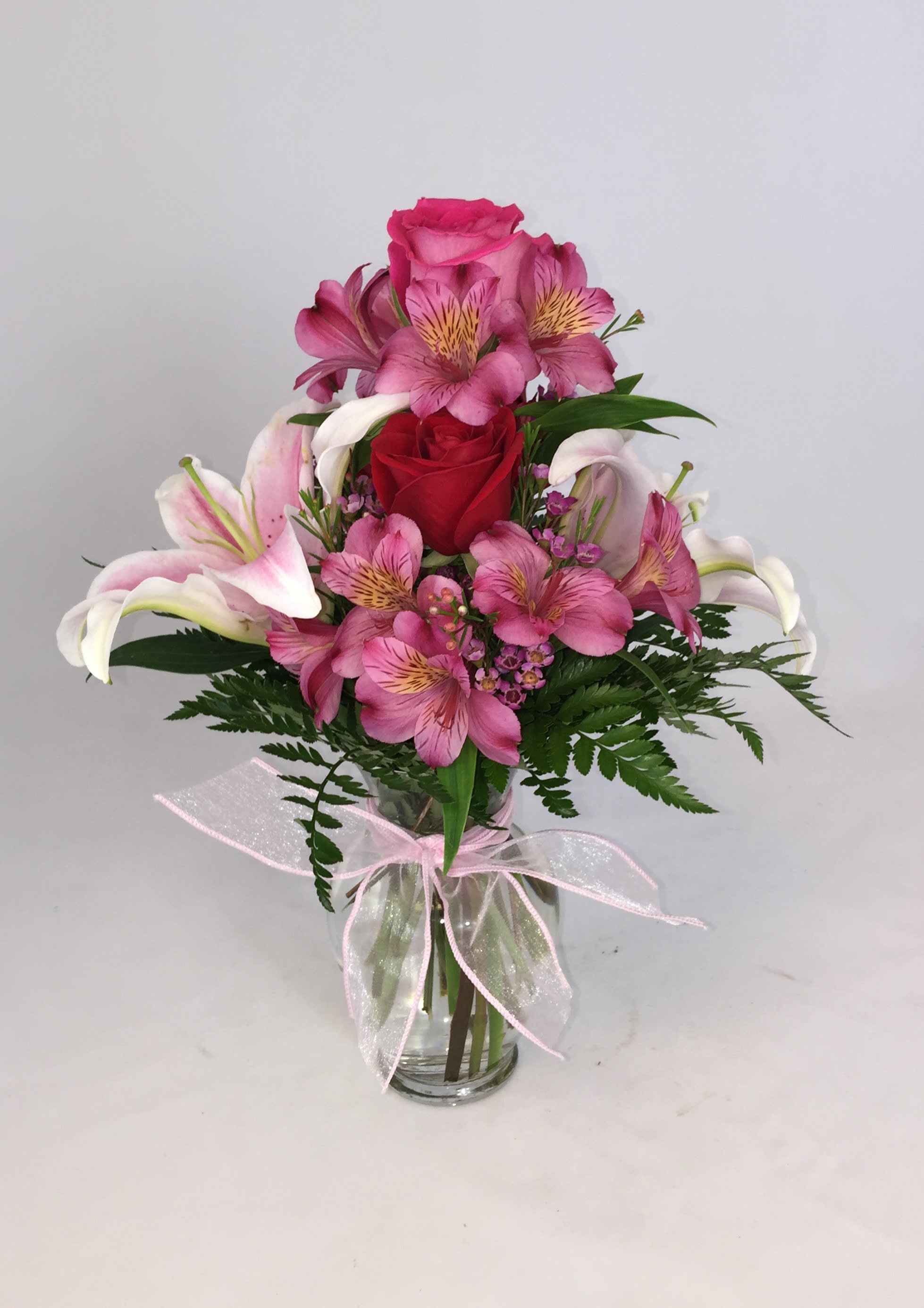 Precious Pink Precious Pink - Pink Lillies, Pink Alstromaria, Pink Roses, and wax flower beautifully arranged in a glass vase with pink bow.