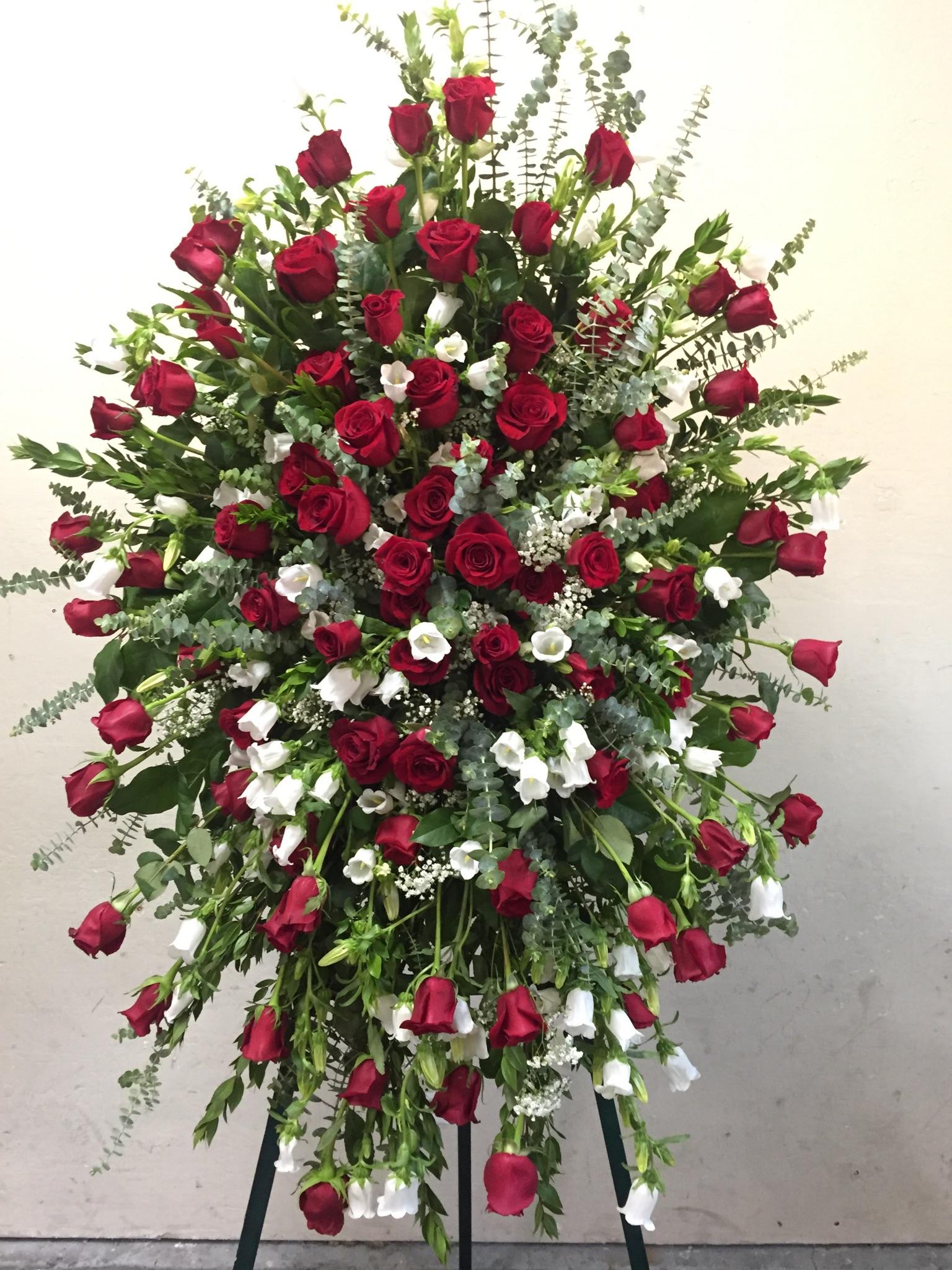Large standing spray of red roses and white flowers on an easel