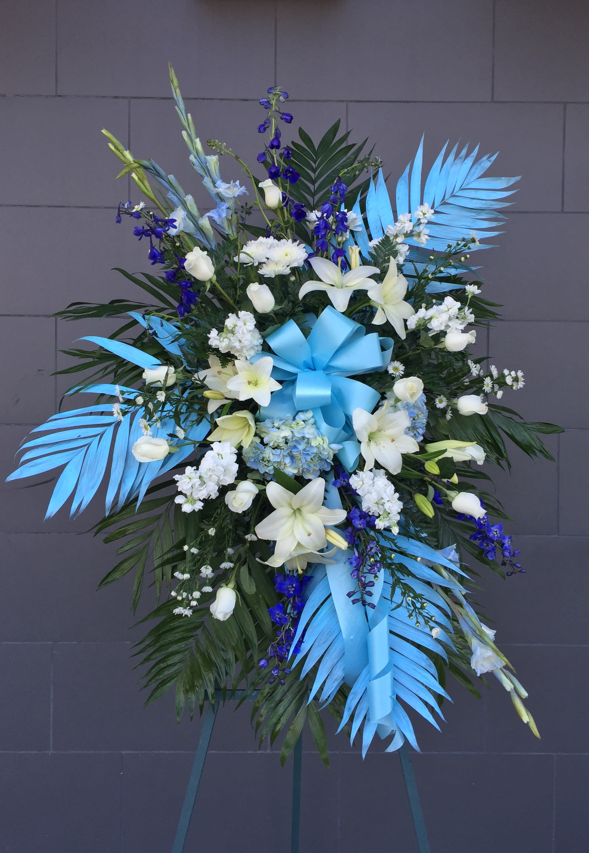 Funeral Spray 1 - Ocean Breeze spray including lily, rose, delphinium... and nice accents. STANDARD: FIRST PHOTO DELUXE: SECOND PHOTO