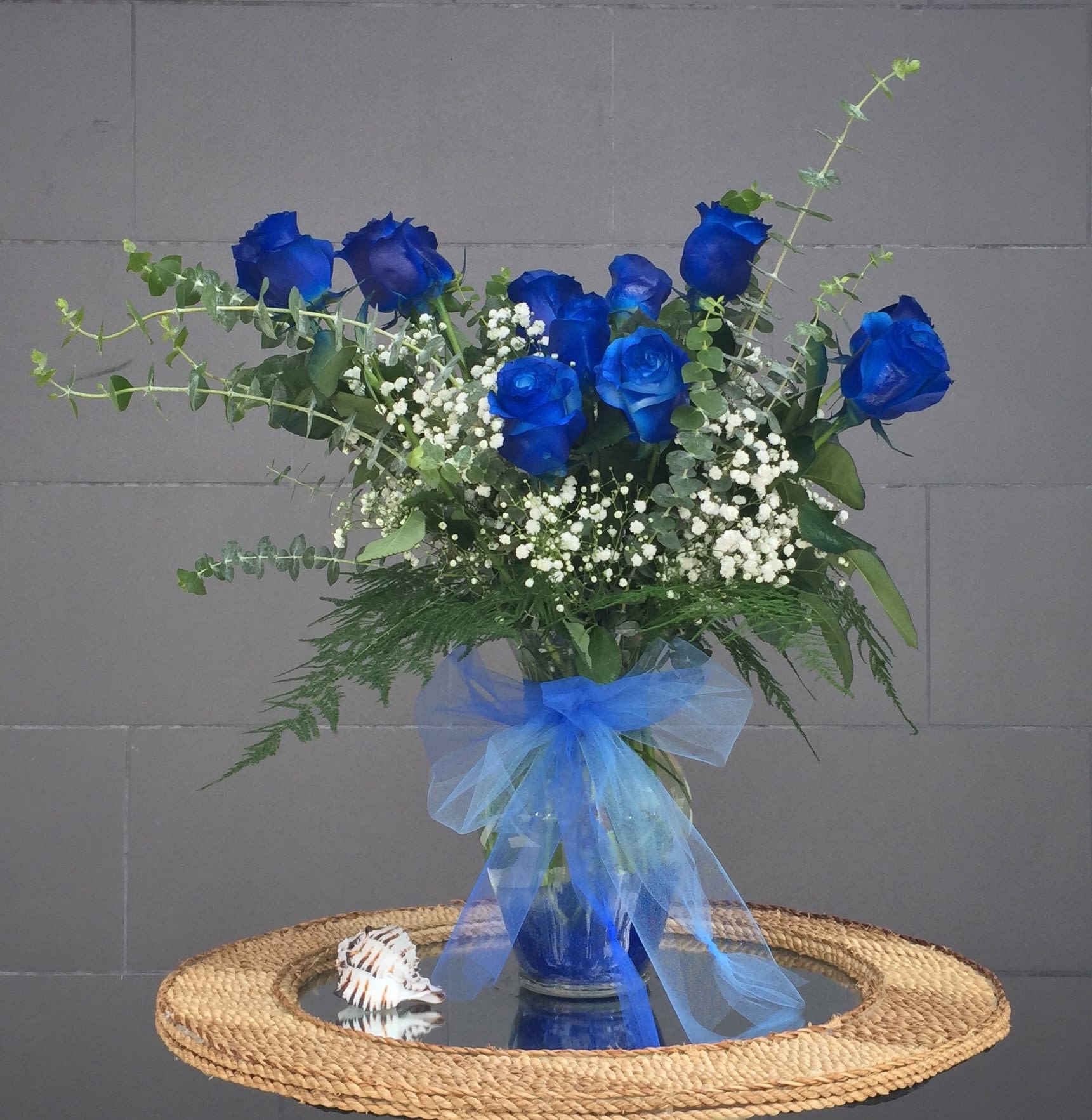 Nautica - Beautiful blue roses and nice accents in a tall glass vase. STANDARD AS SHOWN: 12 ROSES DELUXE: 24 ROSES PREMIUM: 36 ROSES