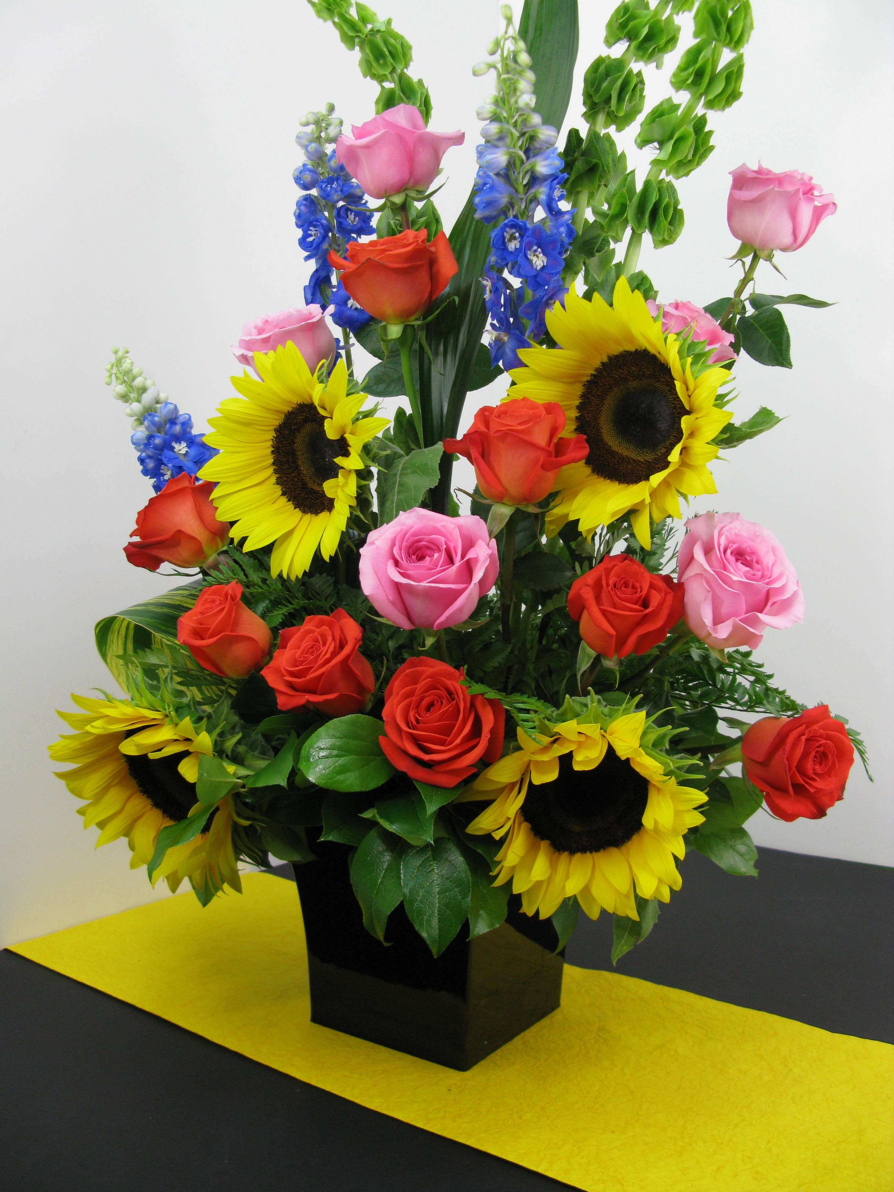 Festive Flowers - A cornucopia of flowers that represent the lively Miami experience. Perfect for any festive occasion this arrangement will bring life and joy to anyone with the roses and sunflowers and original colors it contains.