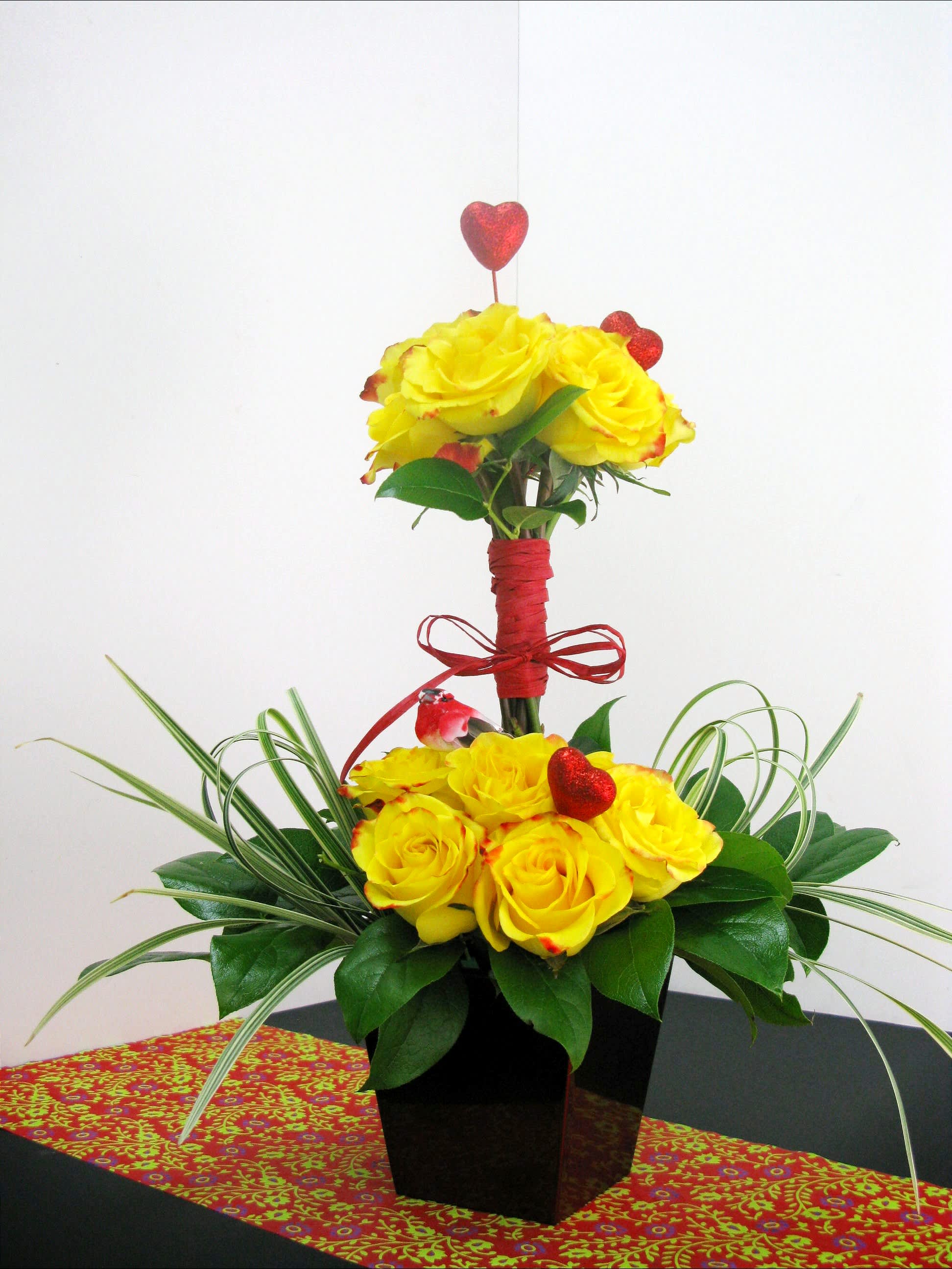 Yellow Topiary Yellow Topiary - This wonderful floral creation includes yellow roses that will light up any room. a lovely bird and red hearts adding a touch of sweetness.