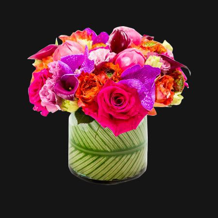 Lovers Paradise -  A collection of coral charm peonies, hot pink vanda orchids, lisianthus, free spirit roses, hot pink roses, calla lilies, and ranunculus in a glass cylinder vase with a leaf wrap.