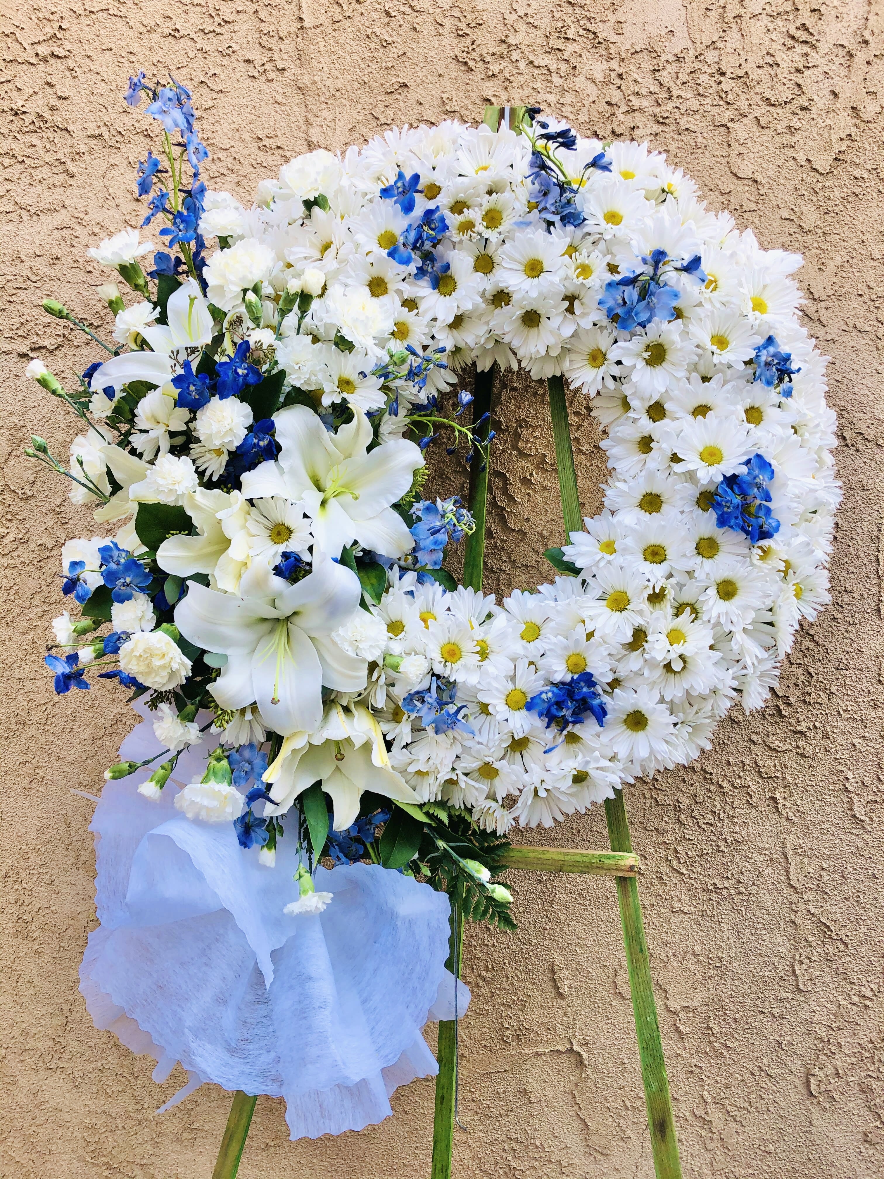 Funearl Wreath 8 - Standing circle funeral spray with white lilies, white daisies, white carnations, and blue daphne flowers. 