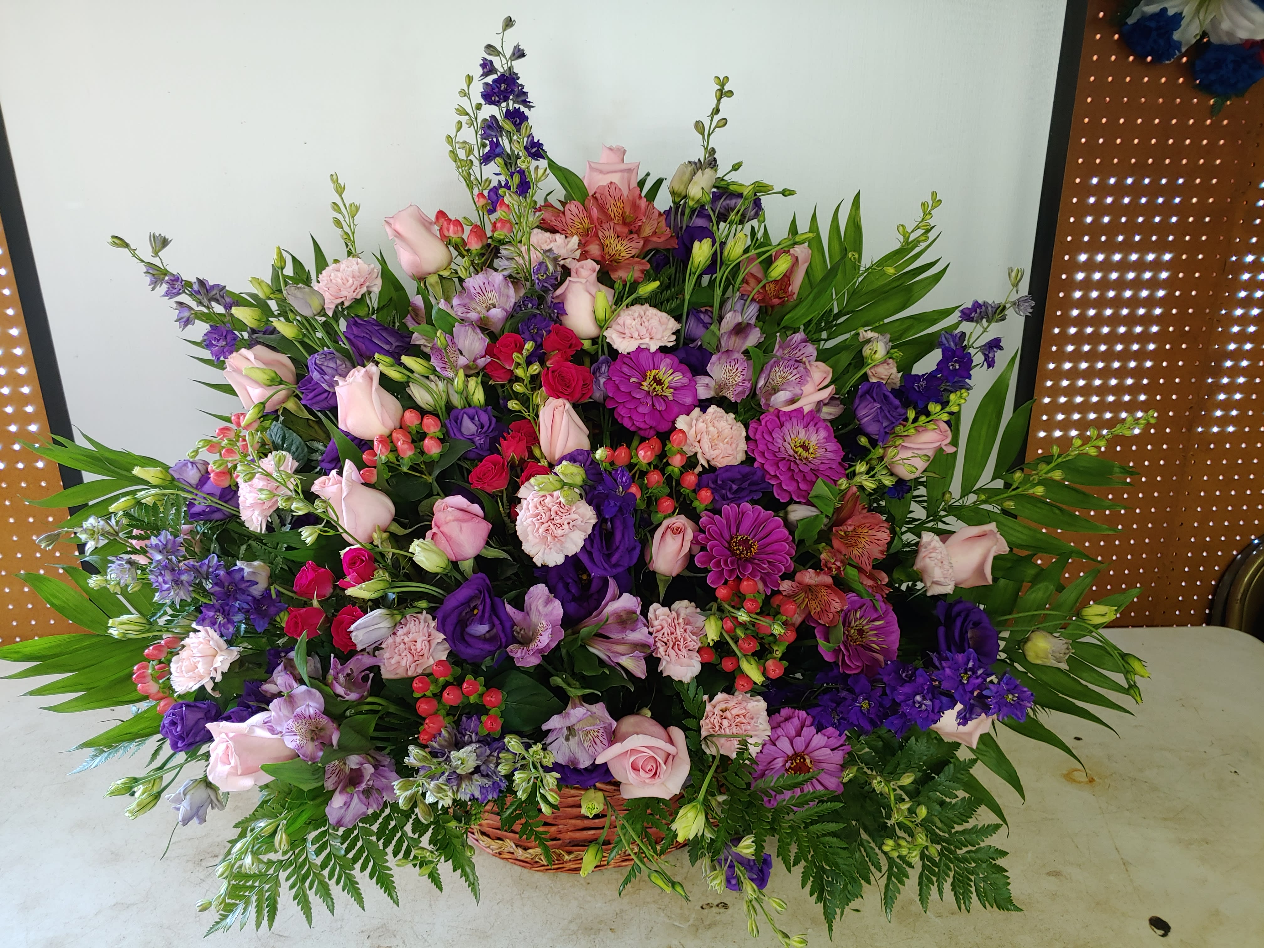 Purple and pink sympathy basket - A wicker basket filled with purple Larkspur and lisianthus, Pink roses and alstromeria, pink spray roses and carnations. 