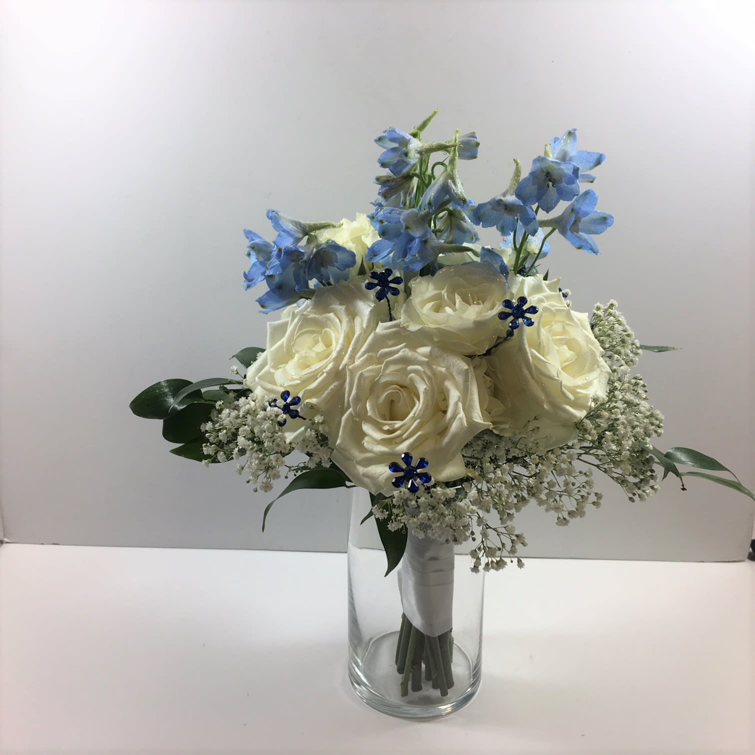 C54 White Clutch with blue C54 White Clutch with blue - White Rose, blue delphinium and blue bling are in this design. Each prom order is customized for your girl's beautiful gown.