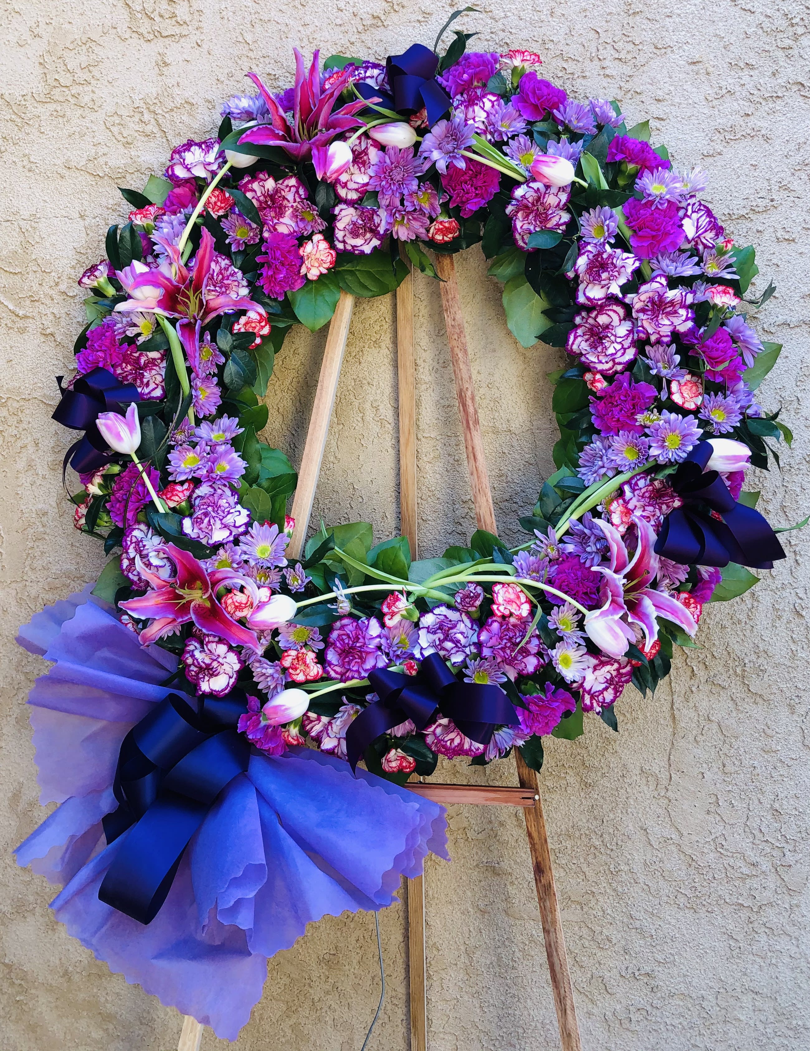 Funeral Wreath 10 - Standing circle funeral spray with mixed purple, white, and pink carnations, lilies, tulips, daisies, and green accents.  