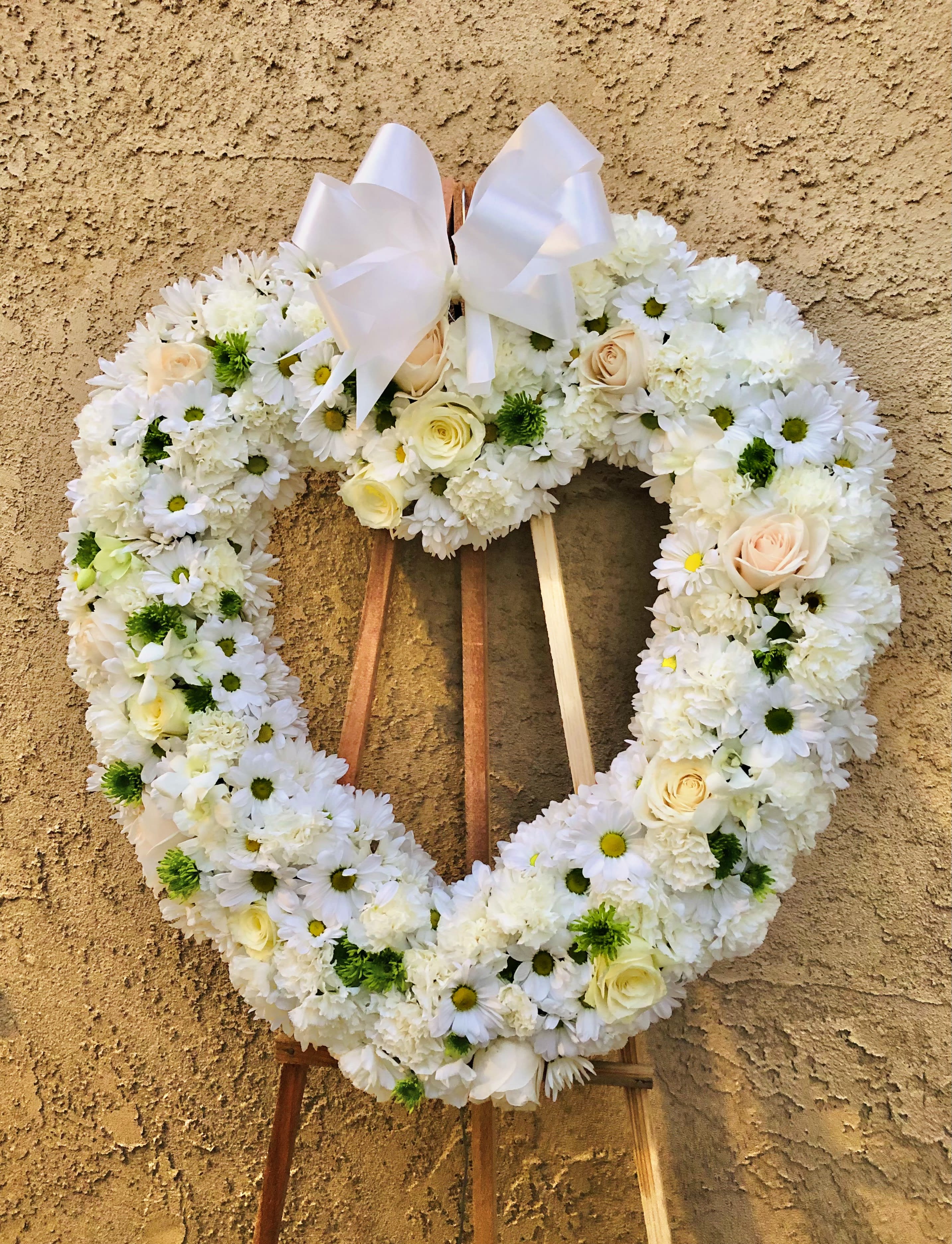 Ribbon Wrapped Love Funeral Spray - Beautiful standing Funeral Spray with white carnations, daisies, roses, and green pompom flowers. Includes a white big ribbon bow. 