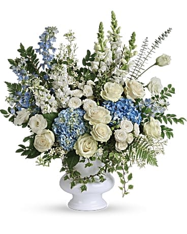 Treasured and Beloved Bouquet - Honor the memory of your beloved with this breathtaking bouquet of sky blue hydrangea and cloud white roses in a classic white urn.         •This beautiful bouquet of light blue hydrangea, white roses, white spray roses, white lisianthus, light blue delphinium, white snapdragons, white stock, and white waxflower is accented with huckleberry, variegated ivy, spiral eucalyptus, dagger fern, and lemon leaf.  •Delivered in a white designer urn.     •Orientation: One-Sided 