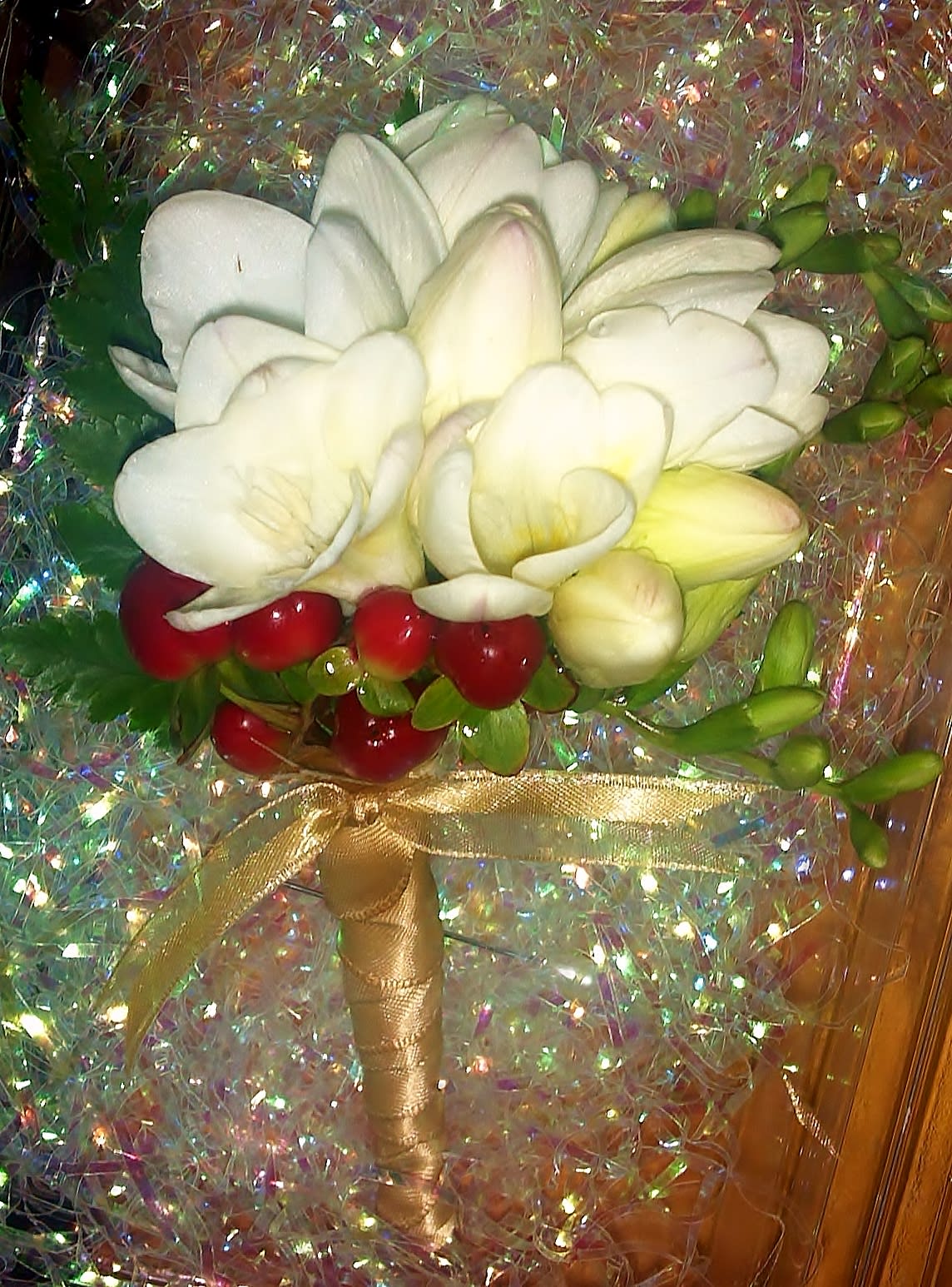 Freesia Boutonniere Freesia Boutonniere - Composed of Freesia blooms, Hypericum berries, and foliage. Long stem design wrapped in Satin ribbon. This design can be made in various colors. Design measures approx. 3"W x 5"H.
