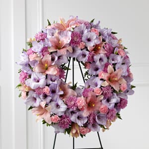 The FTD Sleep in Peace Wreath - The FTD® Sleep in Peace™ Wreath is a soft expression of sympathy that will bring comfort and offer hope during the final farewell. Lavender gladiolus pink Asiatic lilies lavender chrysanthemums pink mini carnations and lush greens are beautifully arranged in the form of a wreath for a sweet and colorful look. Displayed on a wire easel this wreath is a lovely way to honor the life of the deceased.