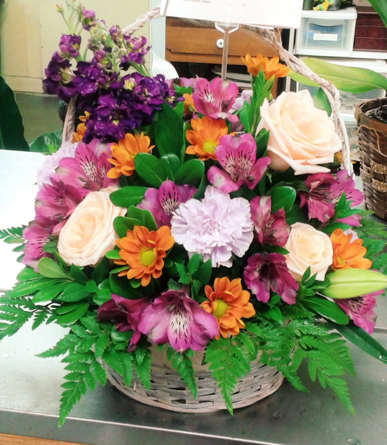 Spring Basket Spring Basket - This basket design includes Roses, Alstroemeria, Mums, Carnations, and Stock set in various foliage. Created with Spring colors in mind. This design measures approx. 12"W x 14"H. Basket may vary.