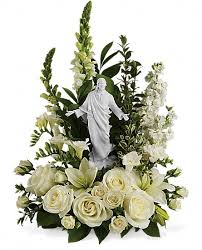 Sacred Grace Sacred Grace - This serene, all white funeral bouquet features a porcelain likeness of Jesus designed by famed artist Stuart Mark Feldman. A sacred choice to send to the church or funeral home, the religious arrangement evokes divine grace and Christian purity. White funeral flowers such as roses, asiatic lilies, stock, snapdragons and freesia are accented with salal, myrtle and pitta negra around a porcelain Sacred Grace keepsake figure.