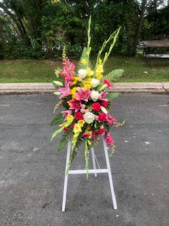 Sweet Pea's Floral 'Shining Light' Standing Spray Sweet Pea's Floral 'Shining Light' Standing Spray - A crescent shaped standing spray, of bright yellows, pinks and whites. Consisting of lilies, gladiolas, roses, snapdragons, daisy poms and carnations. Stand itself is approx. 48" tall.