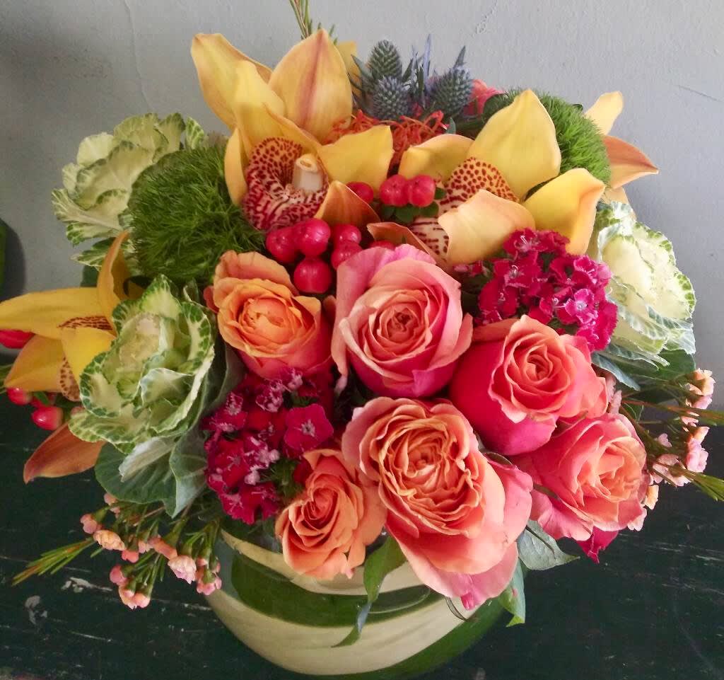 Free Spirit Free Spirit - Tropical color arrangement filled with orange roses, orchids, dianthus, and much more.