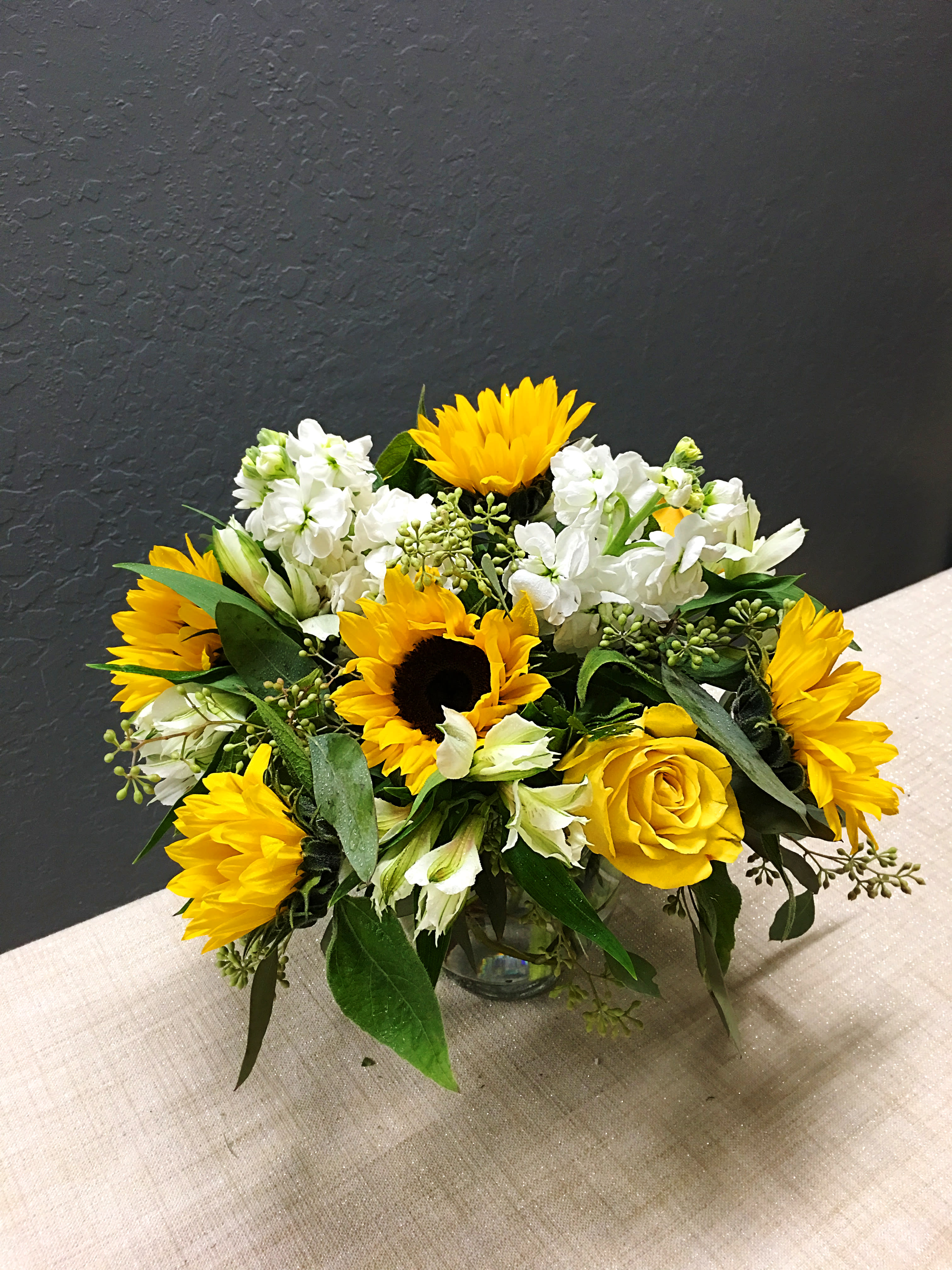 Sunny Bouquet - Bright yellow roses and stunning sunflowers are mixed with white stocks, and white alstroemeria. Presented in a lovely glass bubble bowl. Orientation: All-Around 