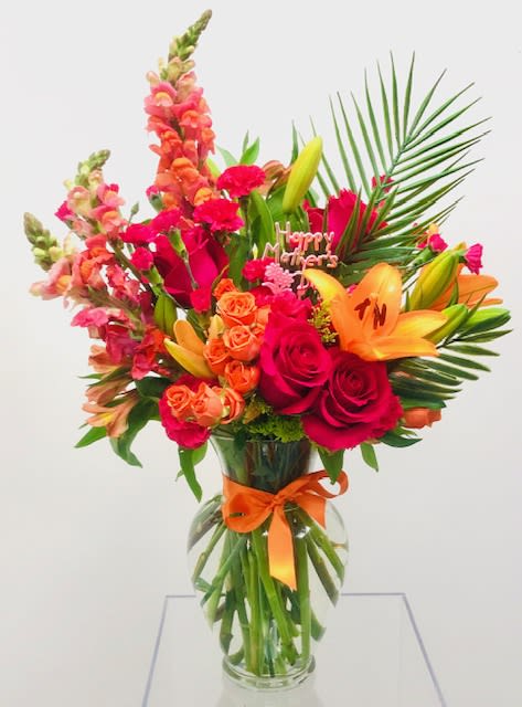 Shazam - Bold display of bright orange and hot pink flowers - lily, roses, spray roses, snapdragon, carnations, palm.  Floral arrangement to be placed in a clear glass vase.  *Please view policy section regarding substitutions.