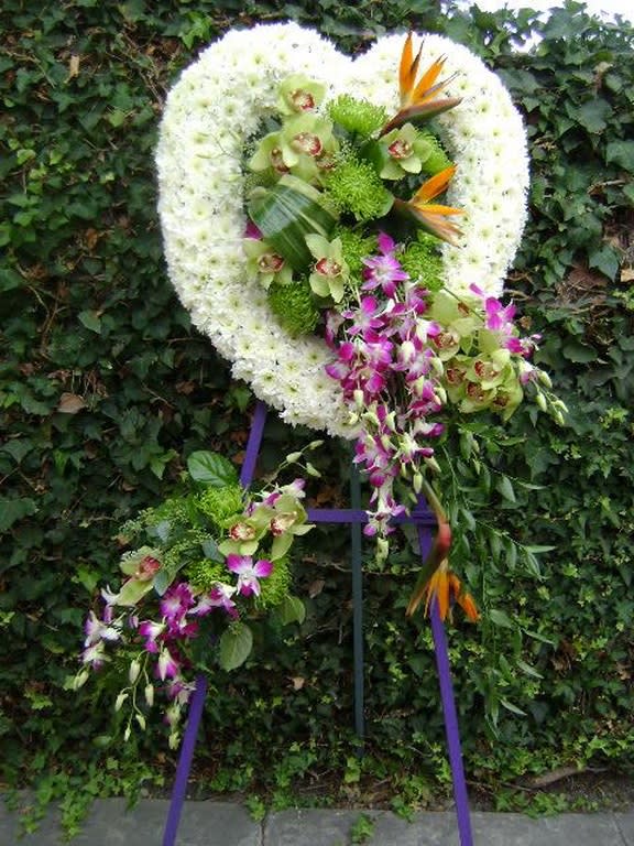 Heart-shaped floral wreath with orchids and bird-of-paradise on a stand