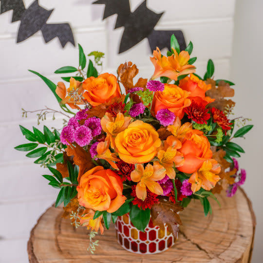 Autumn Radiance Bouquet - Radiant roses and lush fall blooms are presented to perfection in a keepsake mosaic vase of stunning stained glass. This radiant arrangement includes orange roses, light orange alstroemeria, purple button spray chrysanthemums, burgundy cushion spray chrysanthemums, bupleurum, seeded eucalyptus and huckleberry, accented with transparent oak leaves. Delivered in Teleflora's Autumn Radiance Mosaic vase. Orientation: All-Around