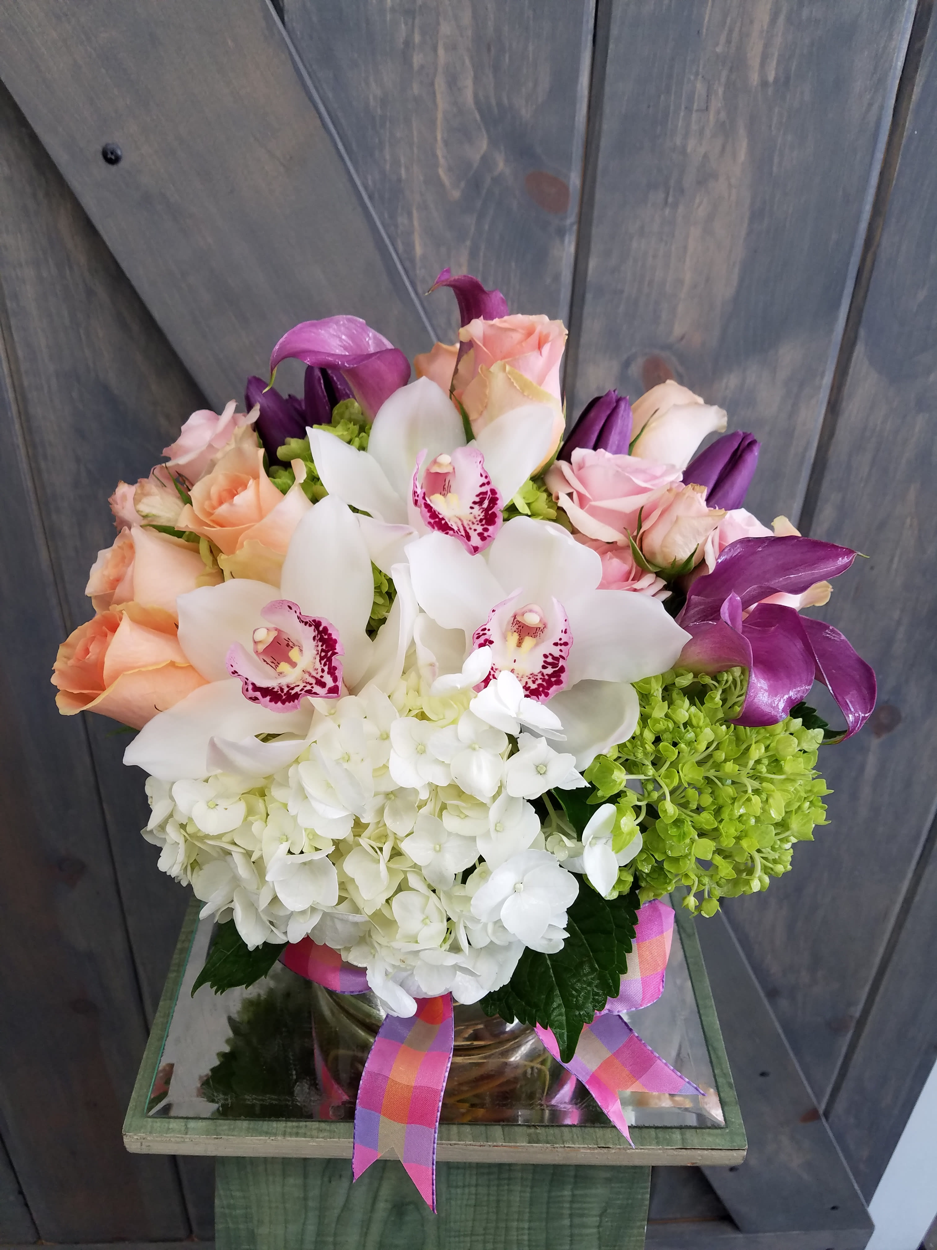 Enchanted Enchanted - This enchantingly beautiful arrangement is designed with a 6in. Cylinder clear glass vase. The Flowers includes are Roses, Spray Roses, Calla Lilies, Tulips, Cymbidium Orchids, Hydrangea, and Mini Green Hydrangea